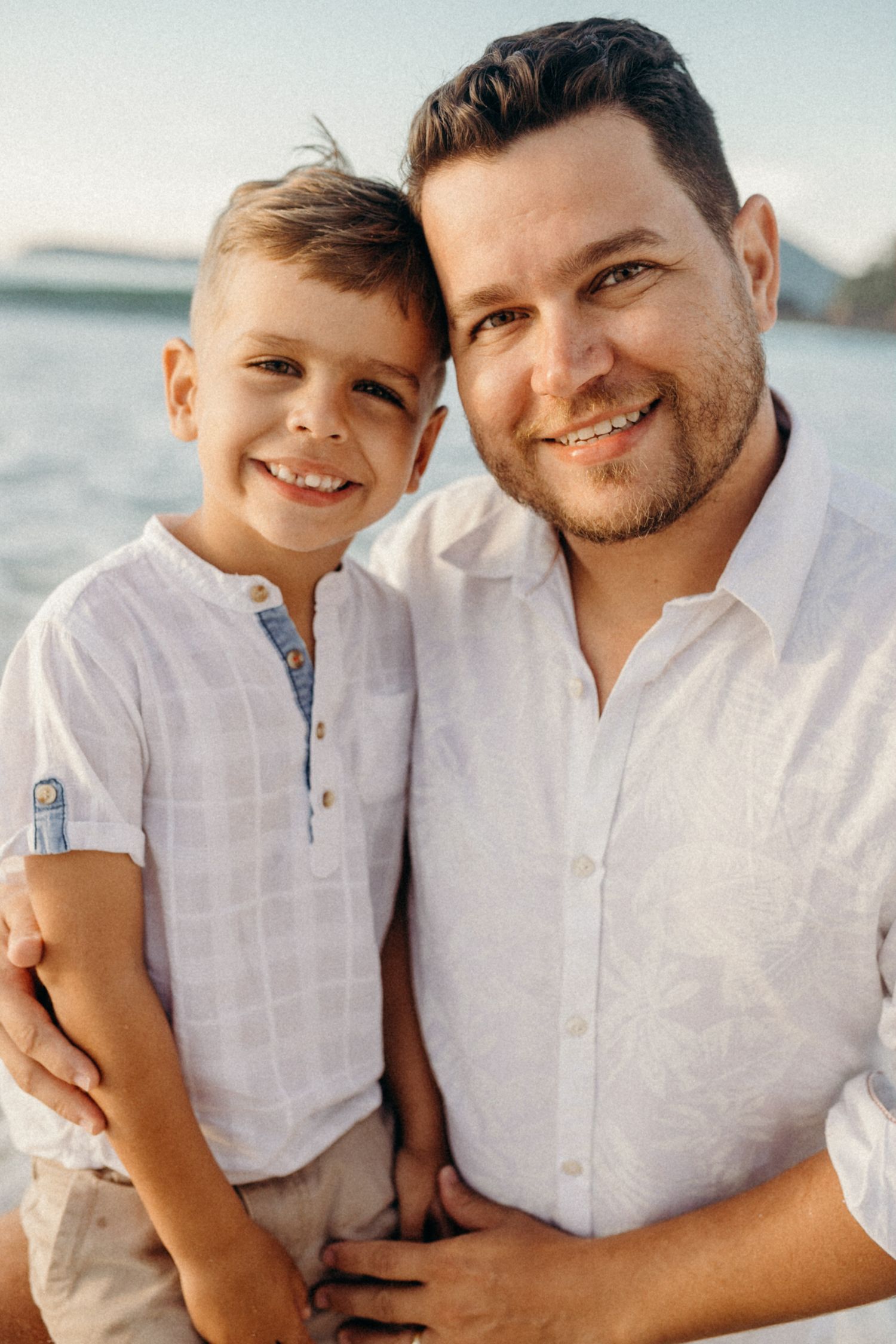 Close-up portrait of happy pair in matching white shirts at the beach.
