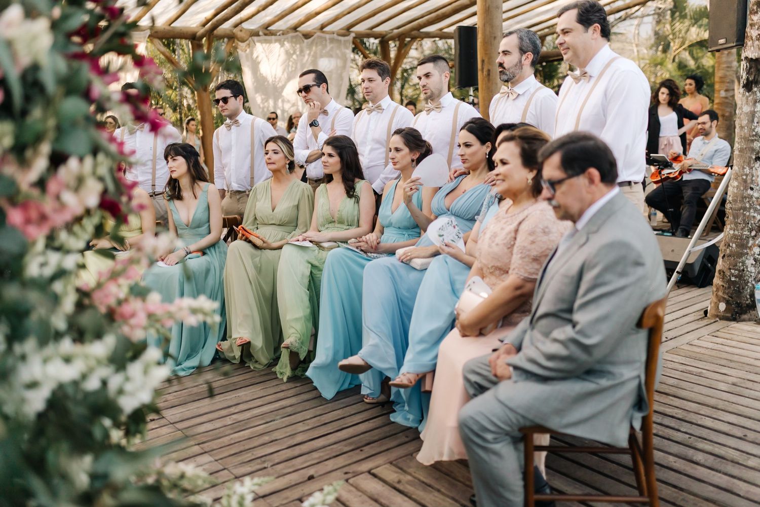 Wedding party and guests seated in formal attire with pastel color scheme.