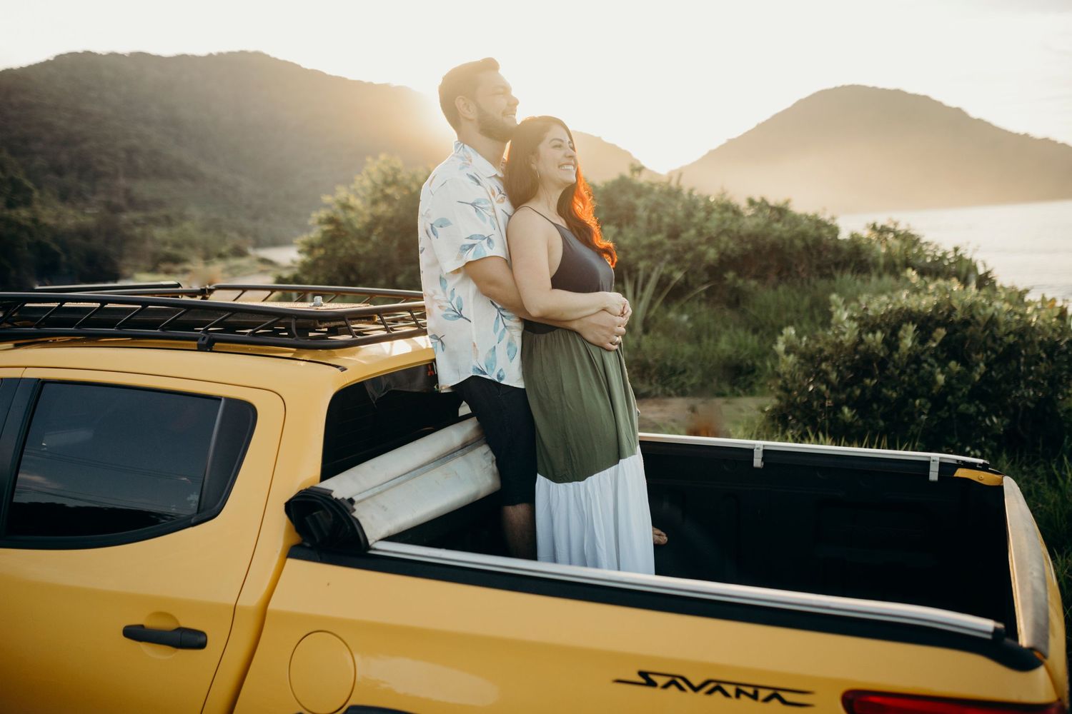 Yellow pickup truck parked against sunset sky with mountain silhouette.