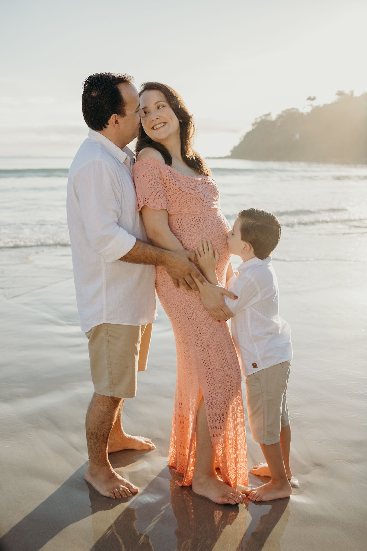 Joyful family moment captured during sunset beach photoshoot with crashing waves.