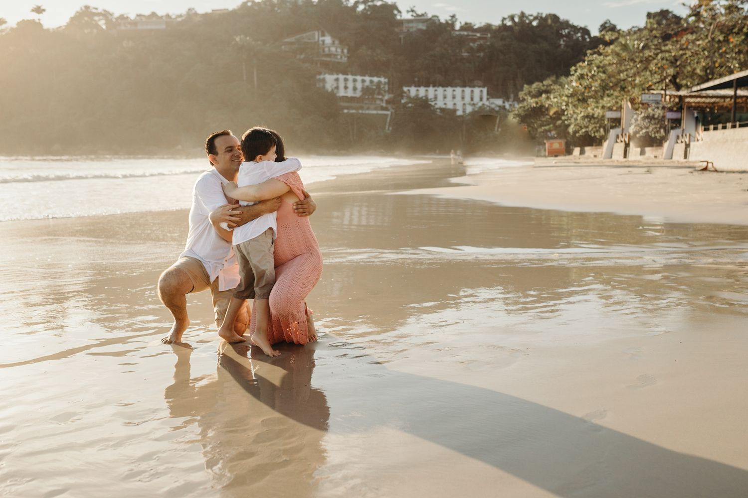 Couple embracing in shallow ocean water during golden hour at beach.