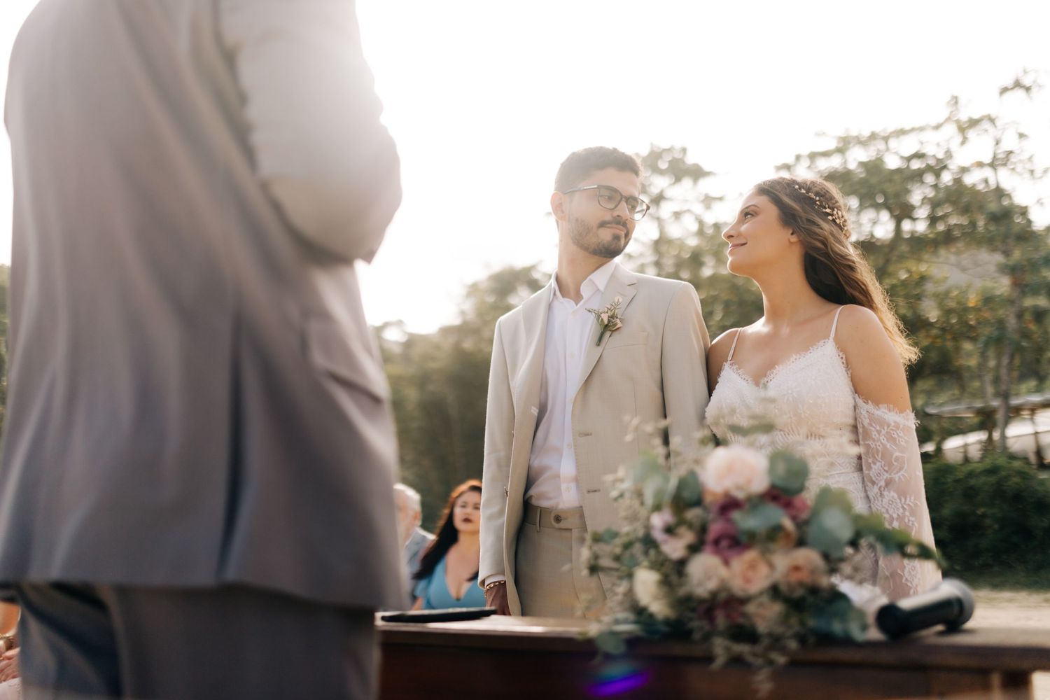 Outdoor beach wedding ceremony with decorated floral arch.