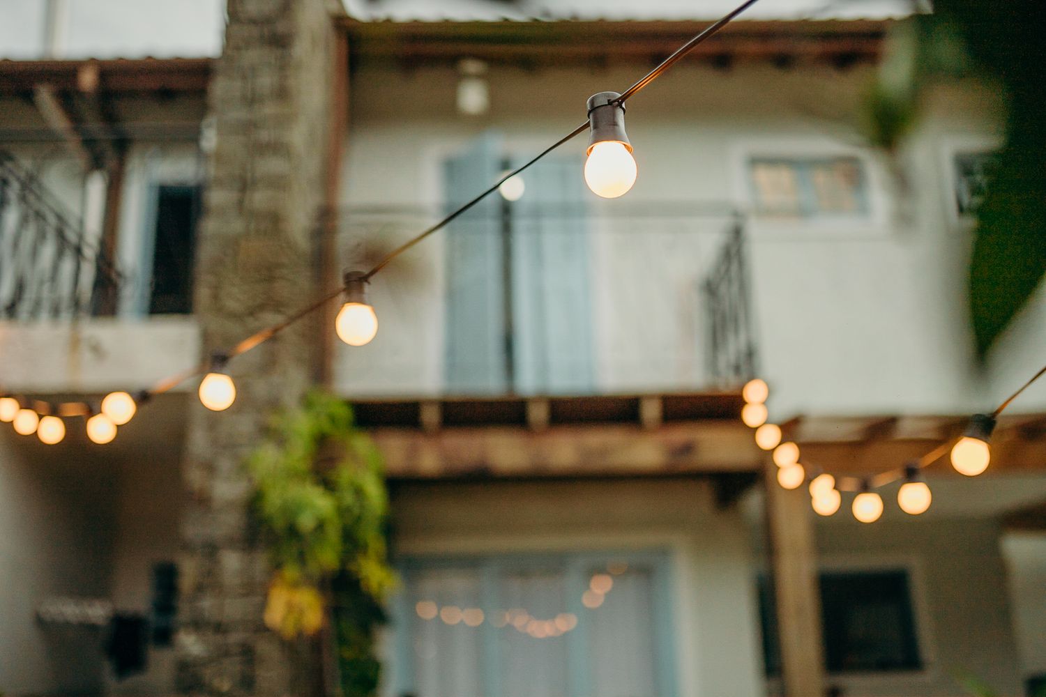 String lights hanging between buildings create a warm ambiance against twilight sky.