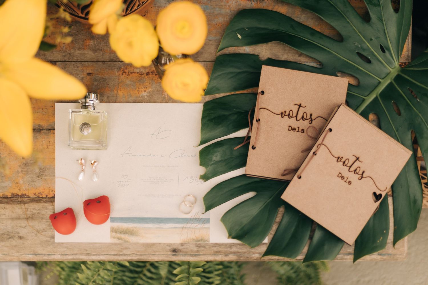 Wedding stationery and details arranged with tropical leaves and warm lighting.