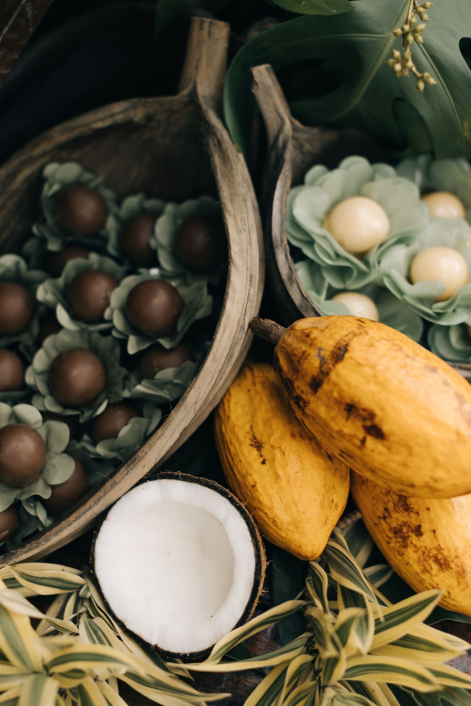 Natural centerpiece with fresh coconuts, yellow fruits, and variegated plants.