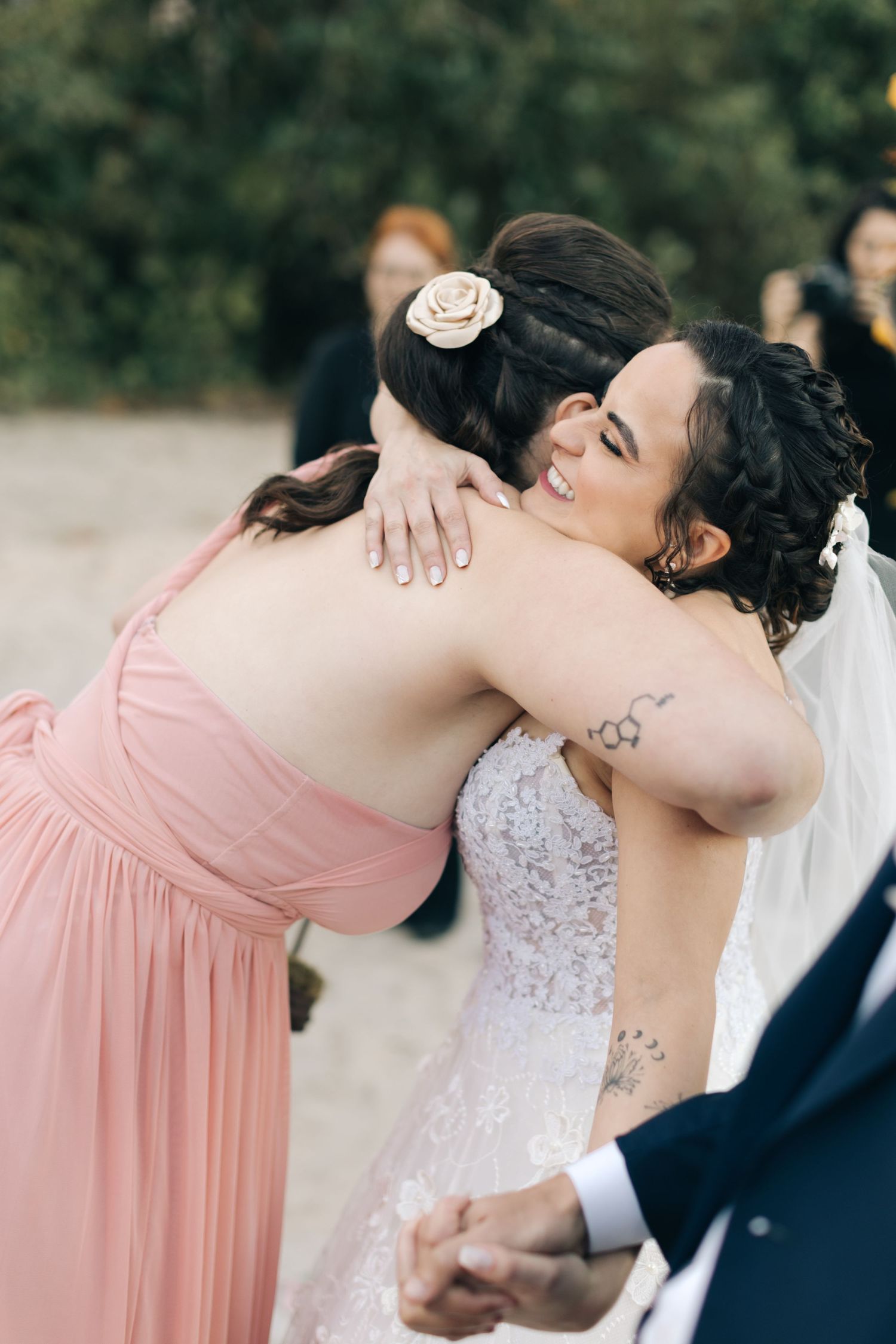 Two people share an emotional embrace during wedding celebration outdoors.