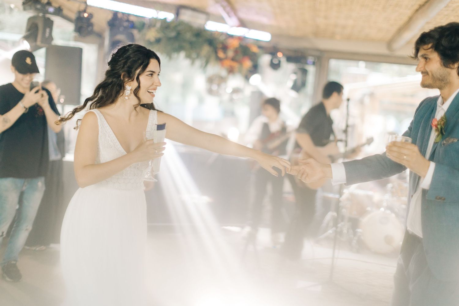 Soft-focused wedding reception scene with guests dancing under ambient lighting.