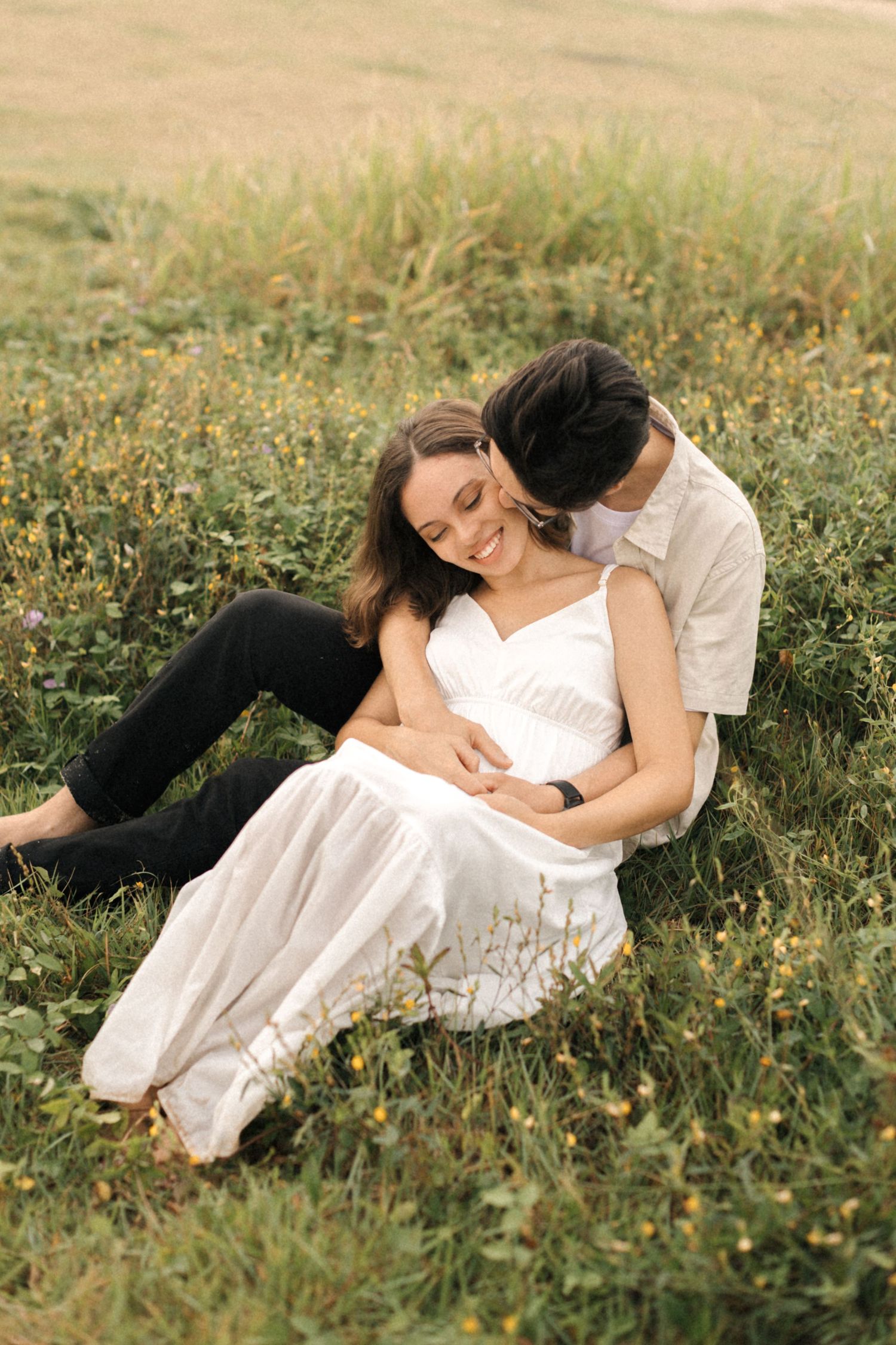 Couple lying together in a wildflower meadow during golden hour photography session.