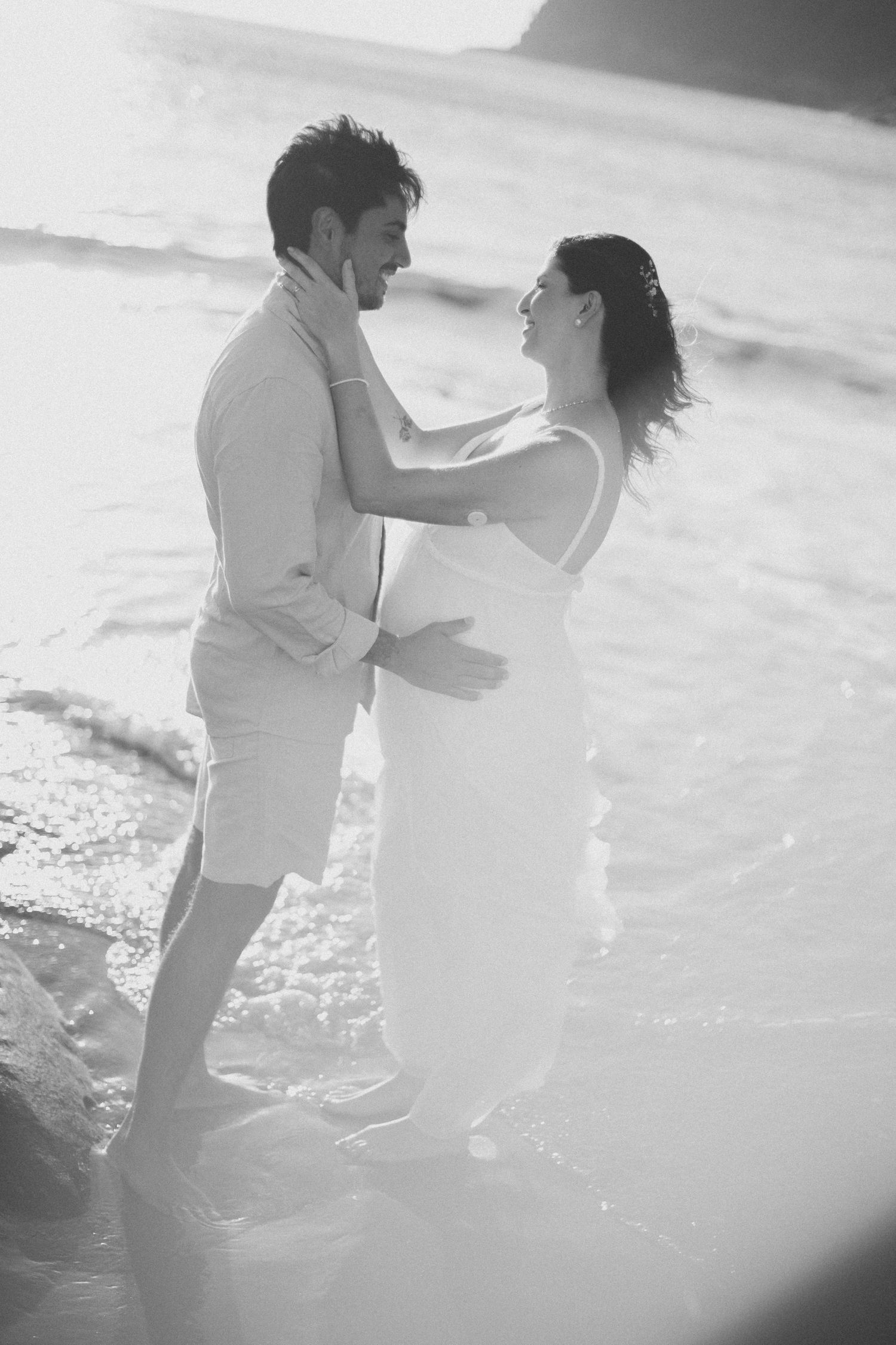 Black and white photo of couple sharing intimate moment on beach during wedding.