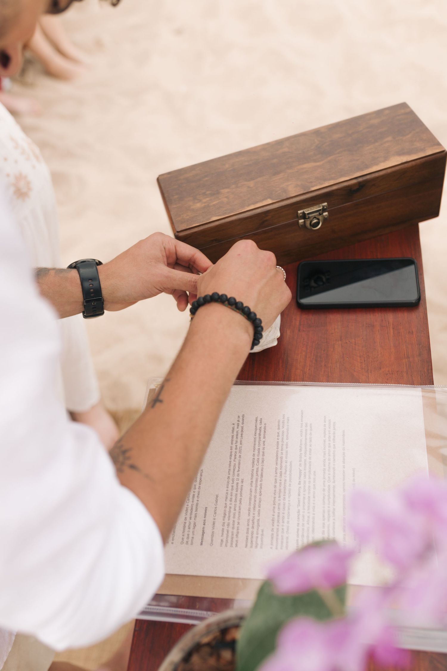 Close-up of hands near a wooden box and documents during an outdoor ceremony.