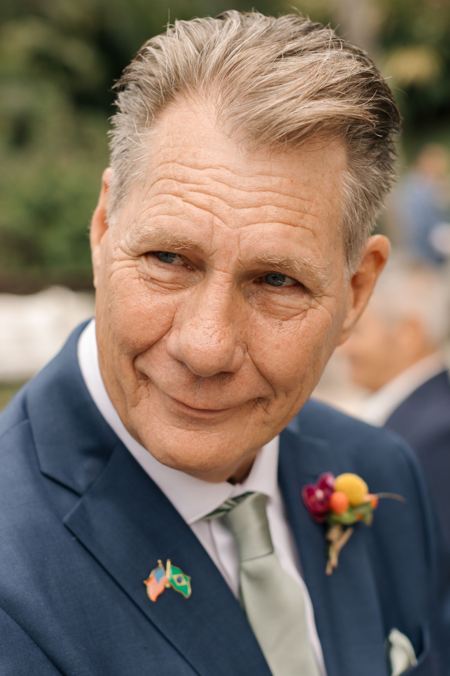 A close-up portrait showing genuine emotion in a navy suit with a colorful boutonniere.