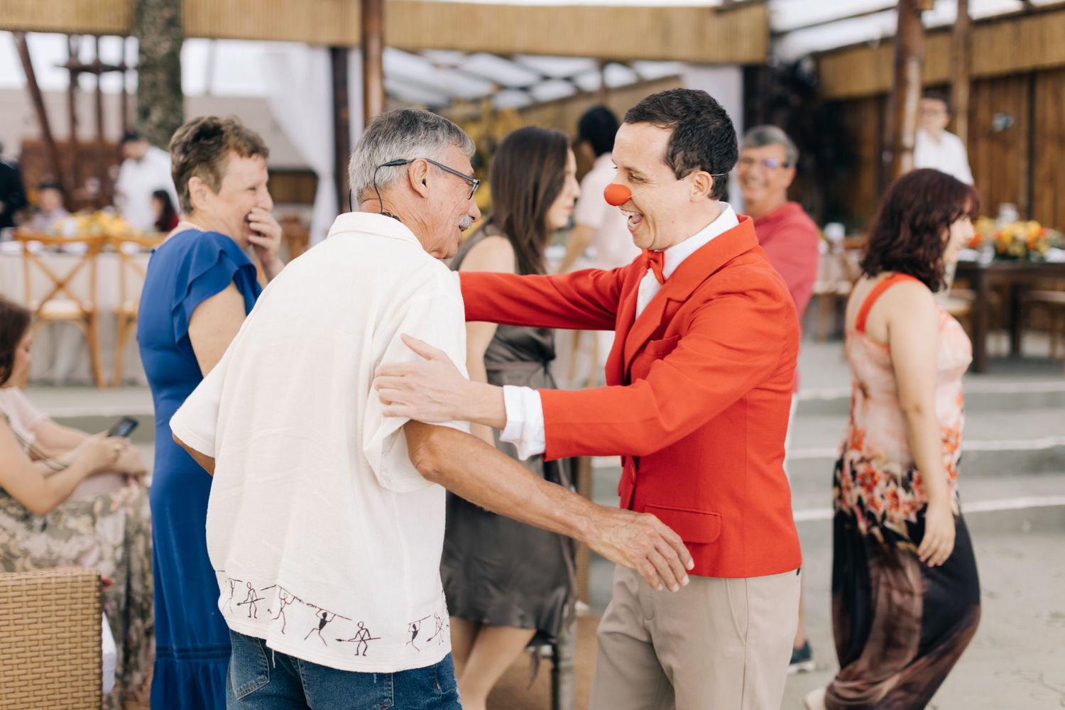 Guests dancing and celebrating at outdoor wedding reception with person in red jacket.