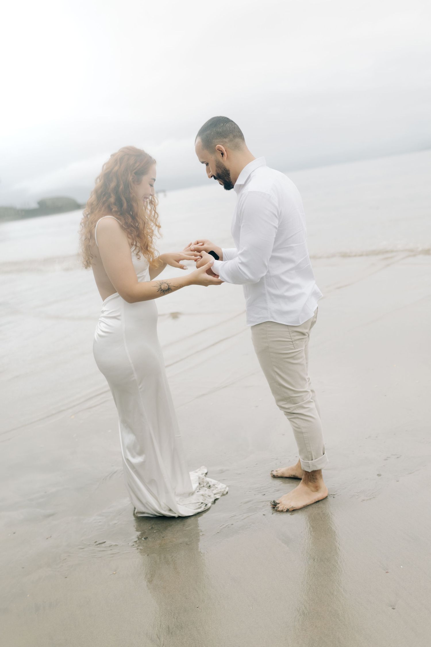 Intimate beachside moment shared between couple in formal attire.