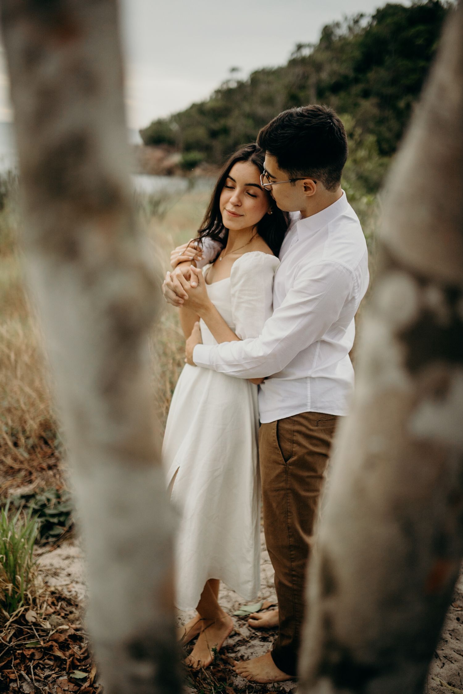 A couple sharing an intimate dance in nature surrounded by tree trunks.