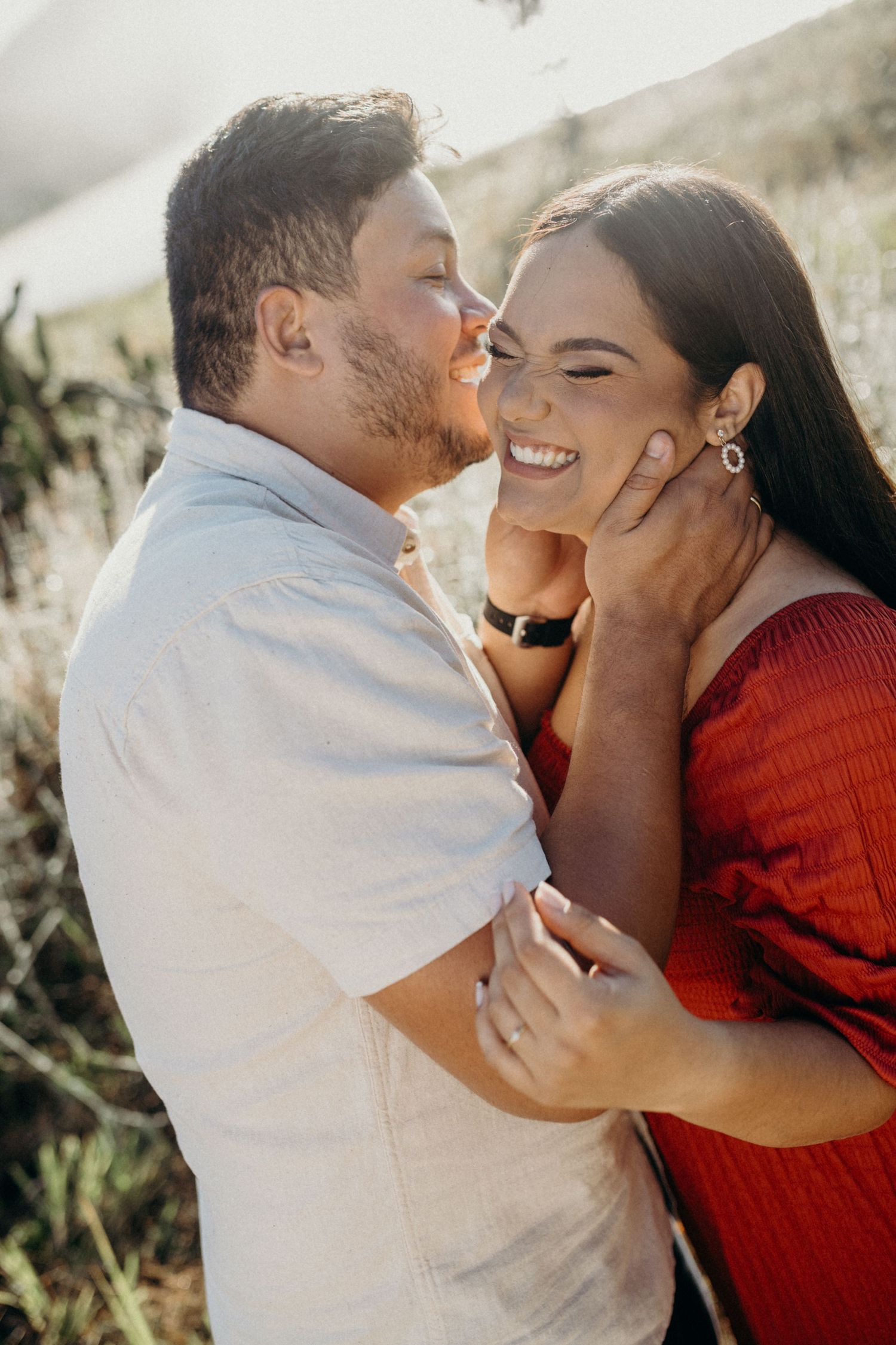 A couple shares intimate kisses outdoors while wearing red and white outfits.