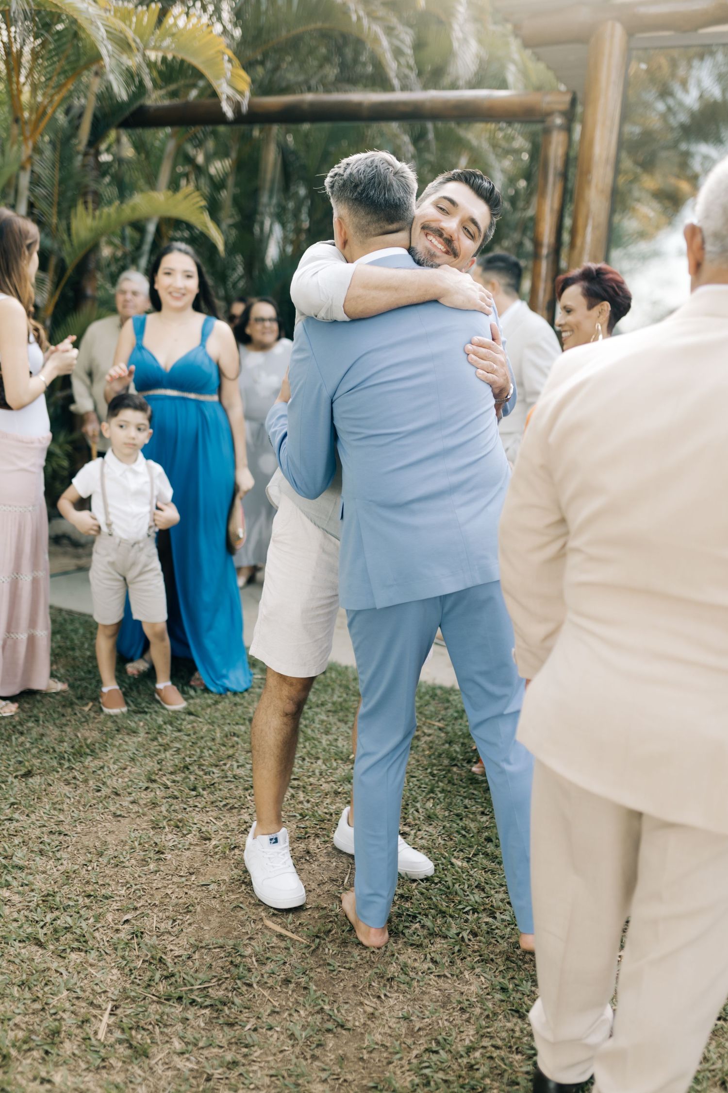 Two people sharing an emotional embrace at an outdoor wedding celebration.