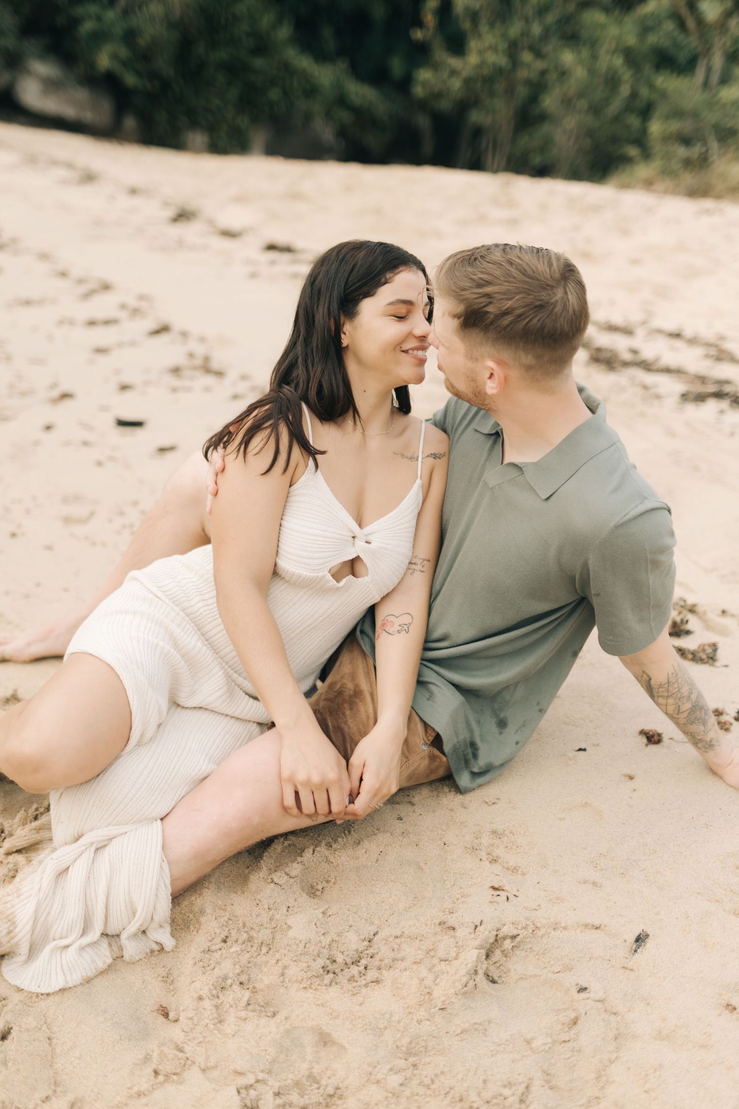 Romantic couple lying together on a sandy beach during an intimate photoshoot.