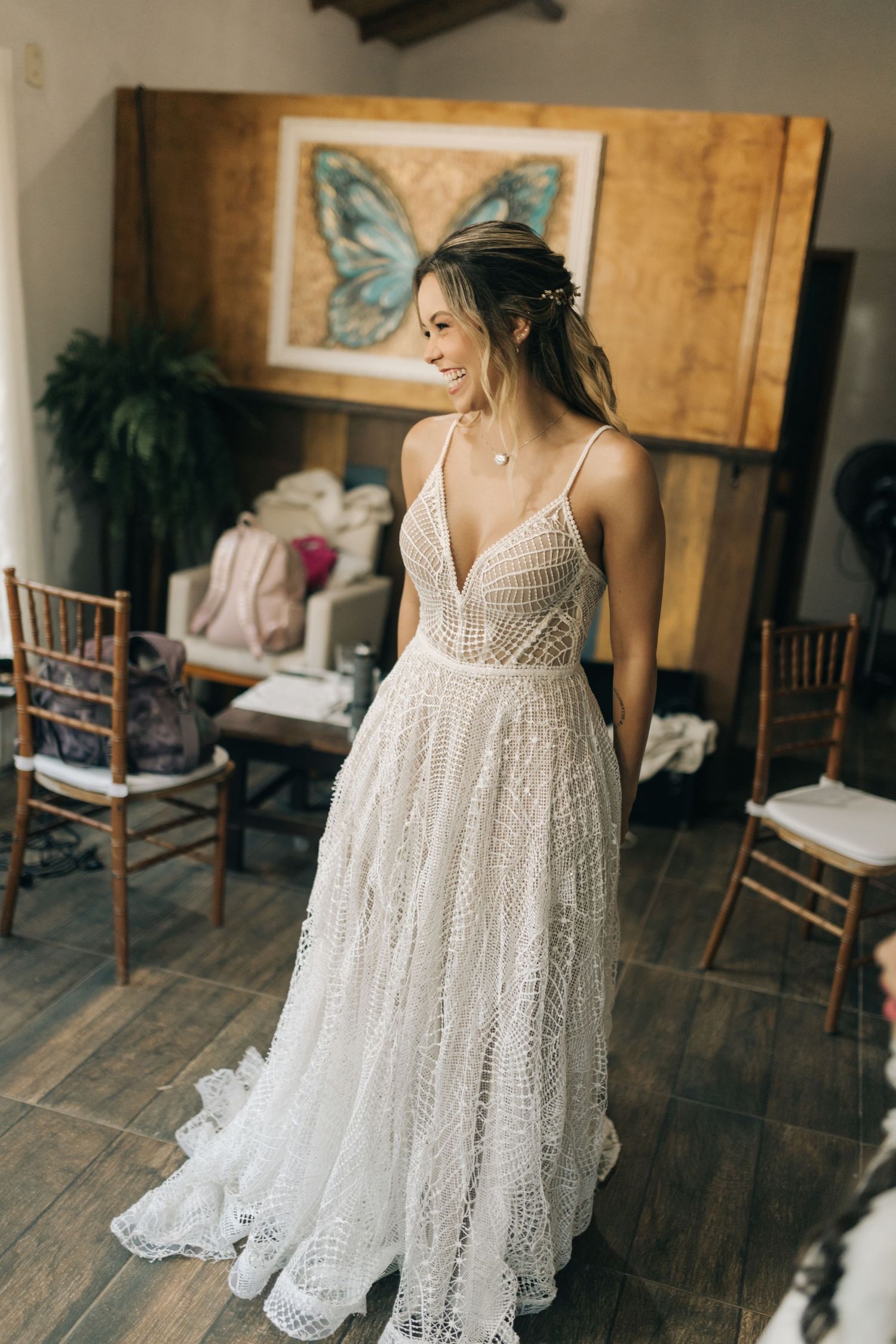 A detailed view of an intricate white lace wedding dress in a rustic venue setting.