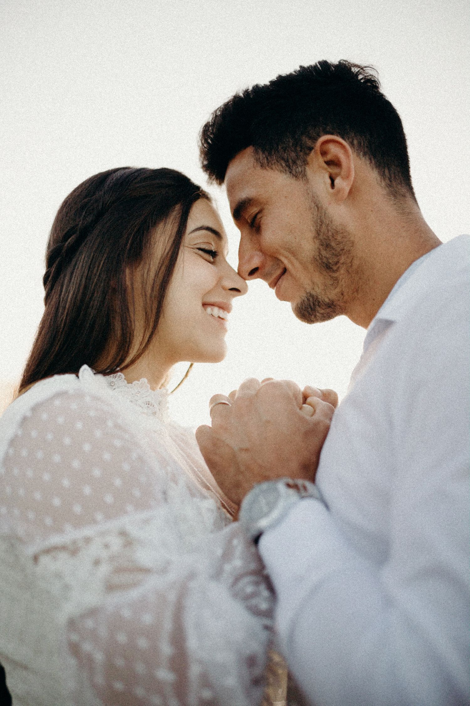 Romantic couple sharing an intimate moment with closed eyes in soft lighting.