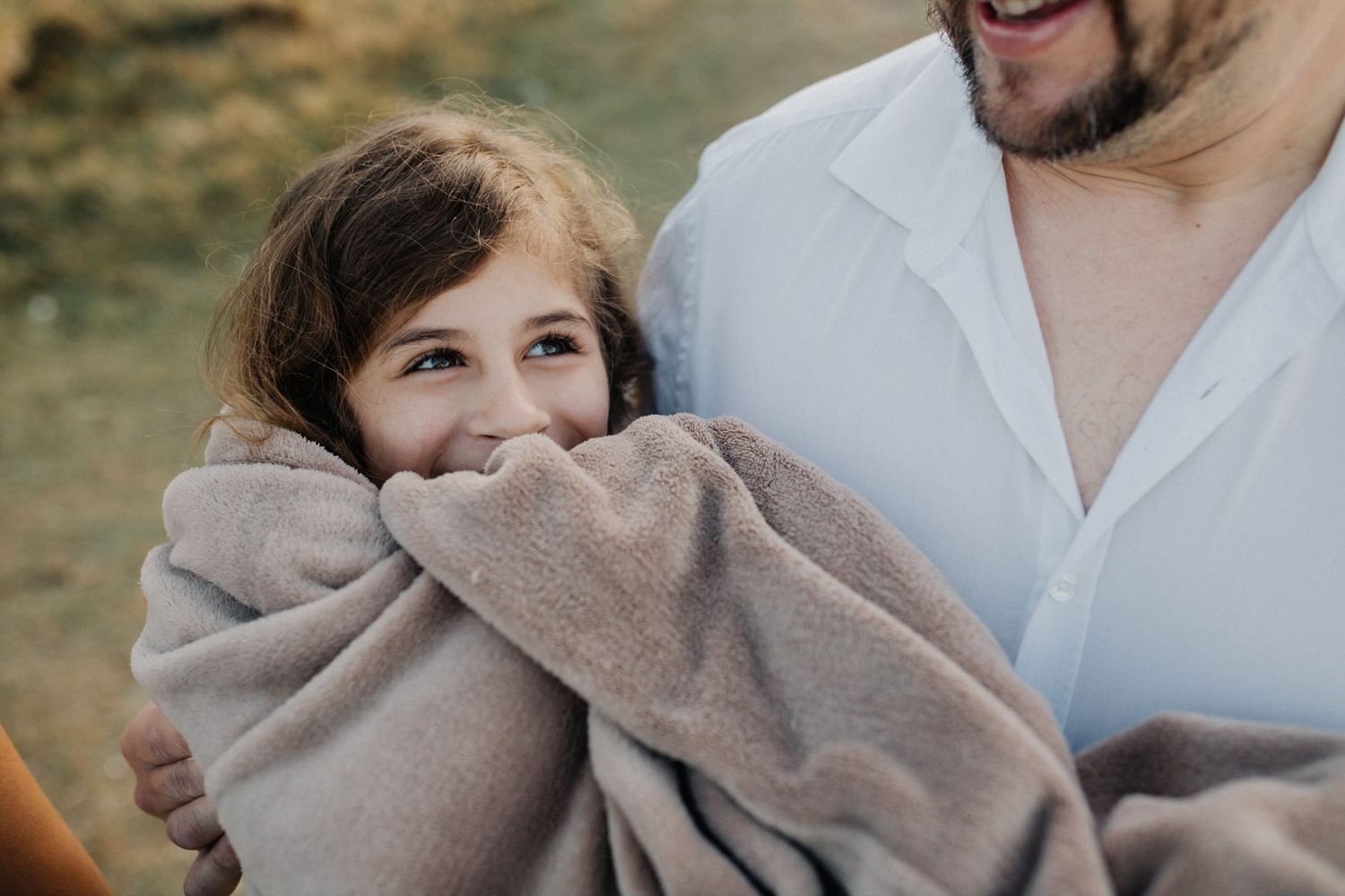 Candid family photo showing joyful expressions and shared laughter outdoors.