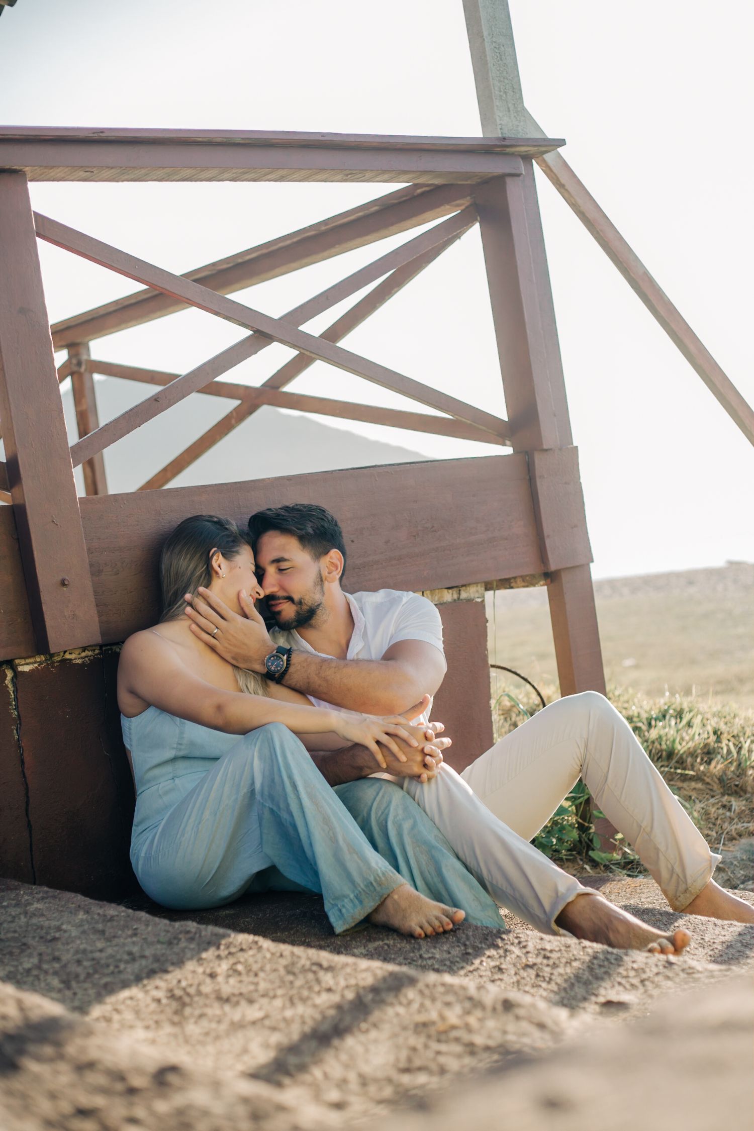 Intimate outdoor portrait of couple embracing on wooden porch during golden hour.