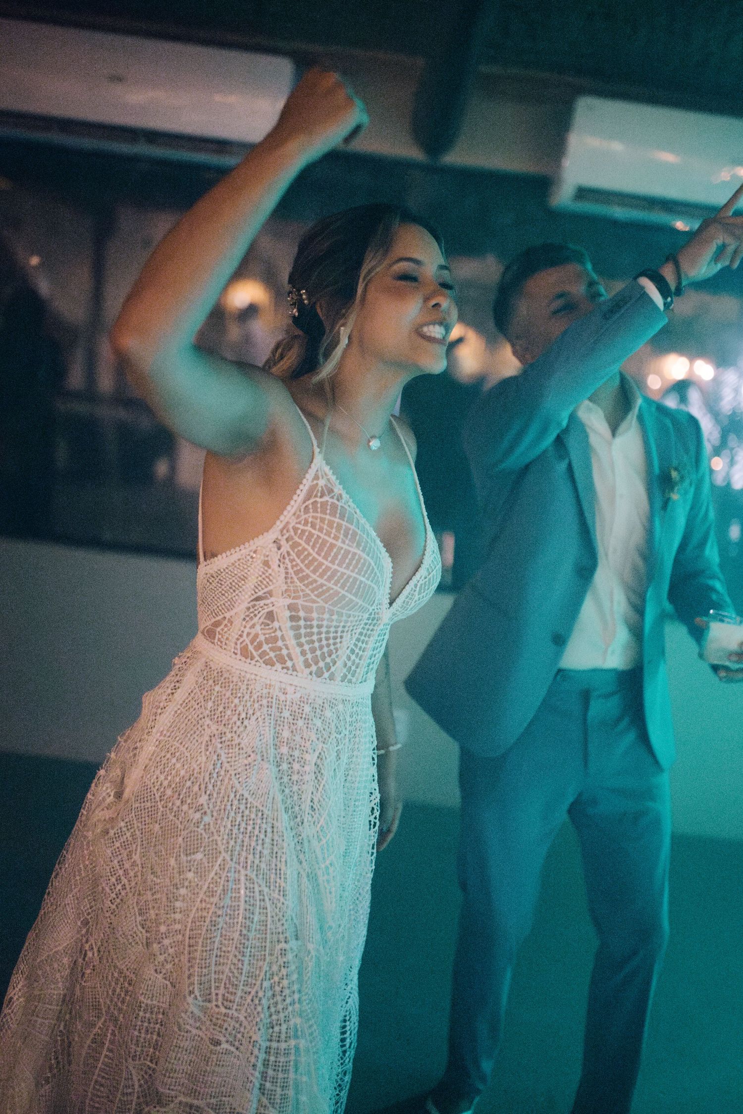 Dance party at wedding reception with blue lighting and energetic atmosphere.