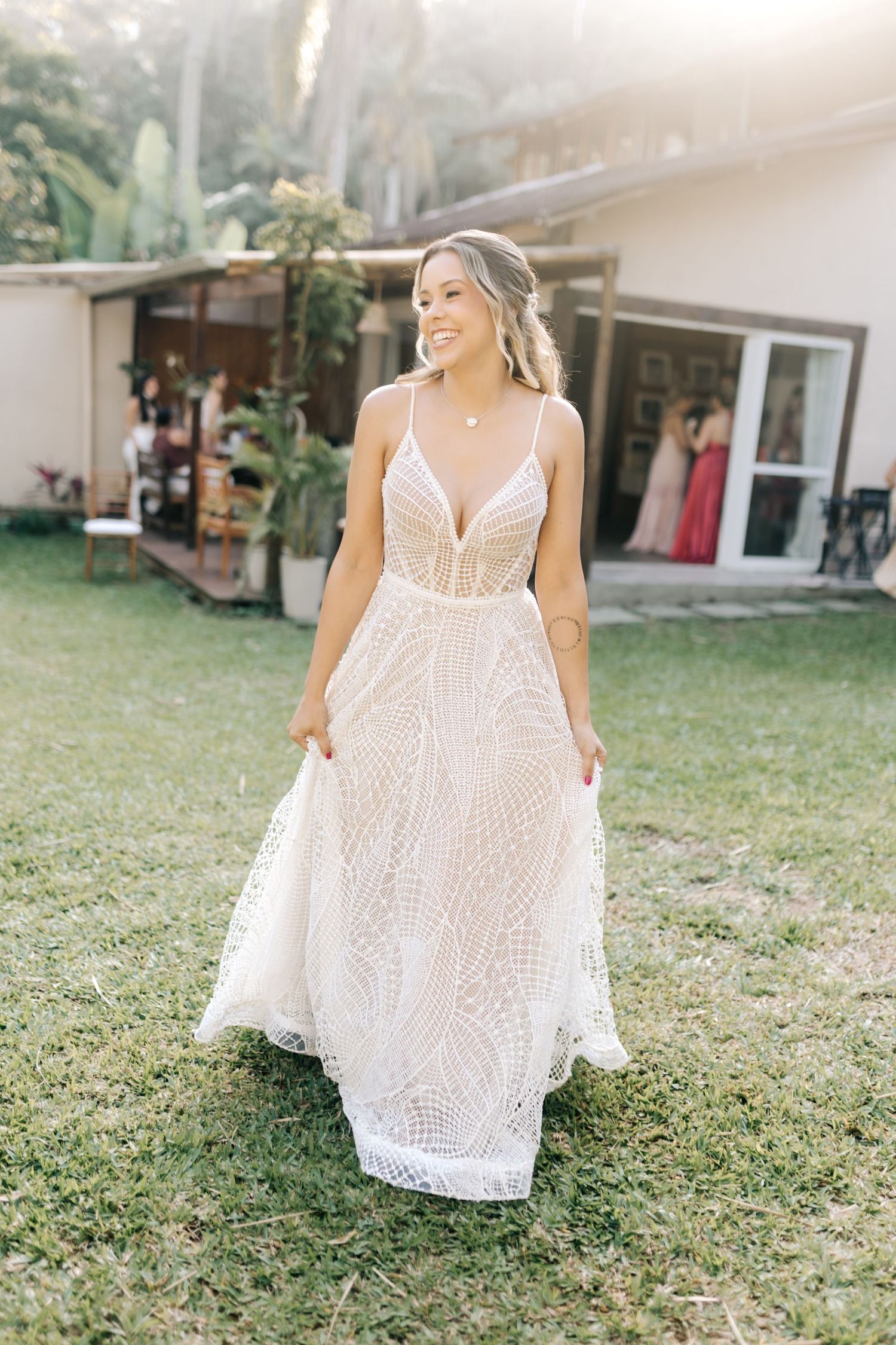 A flowing white lace wedding dress showcased on a grassy lawn in natural lighting.