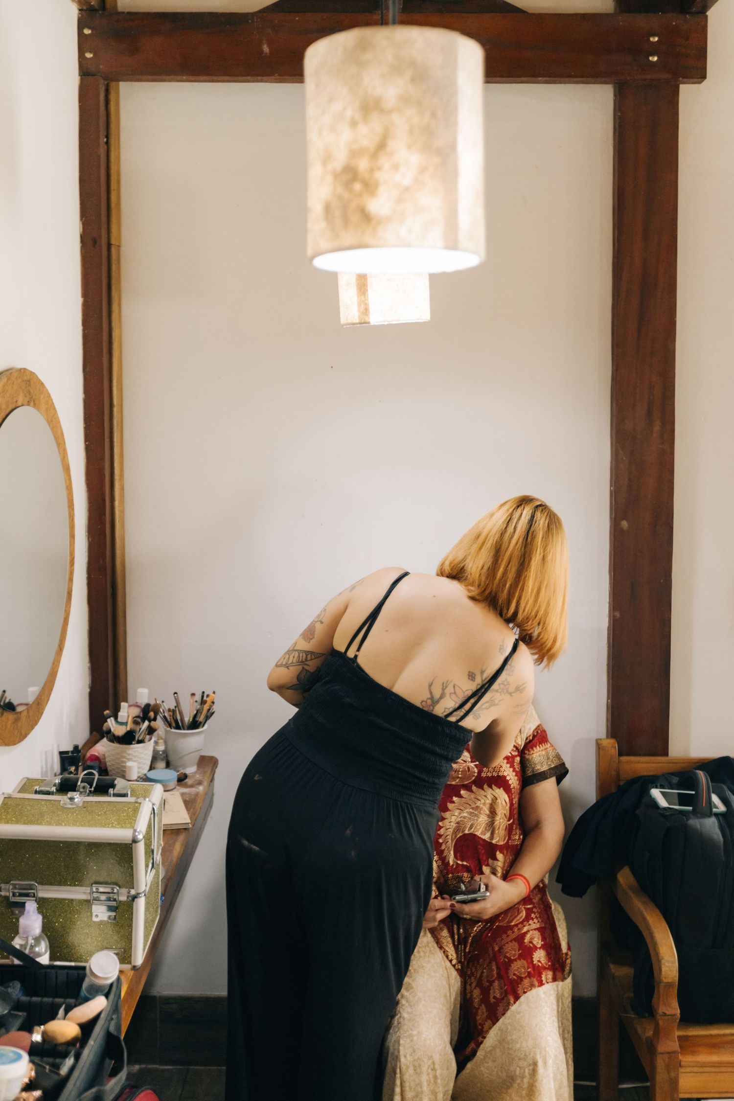 Hairstylists work in a salon with exposed wooden beams and natural lighting.