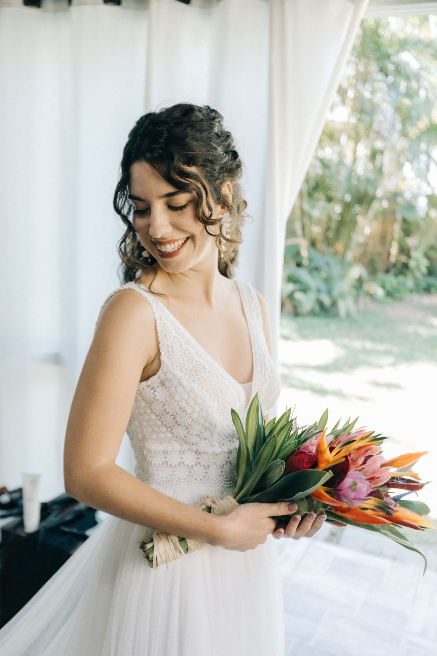 A wedding bouquet of tropical flowers and birds of paradise held against a white dress.