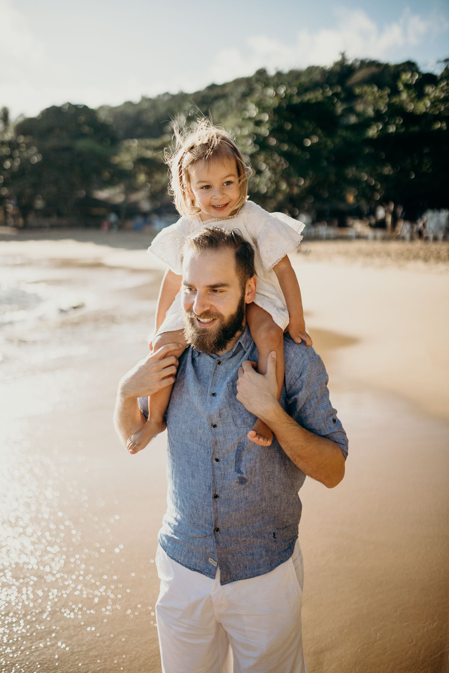 Joyful piggyback ride along a serene beach with mountains in the background.