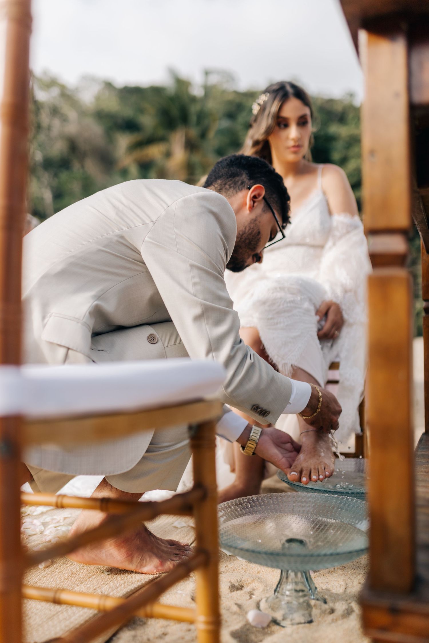 Traditional foot washing ceremony during wedding with couple in elegant attire.