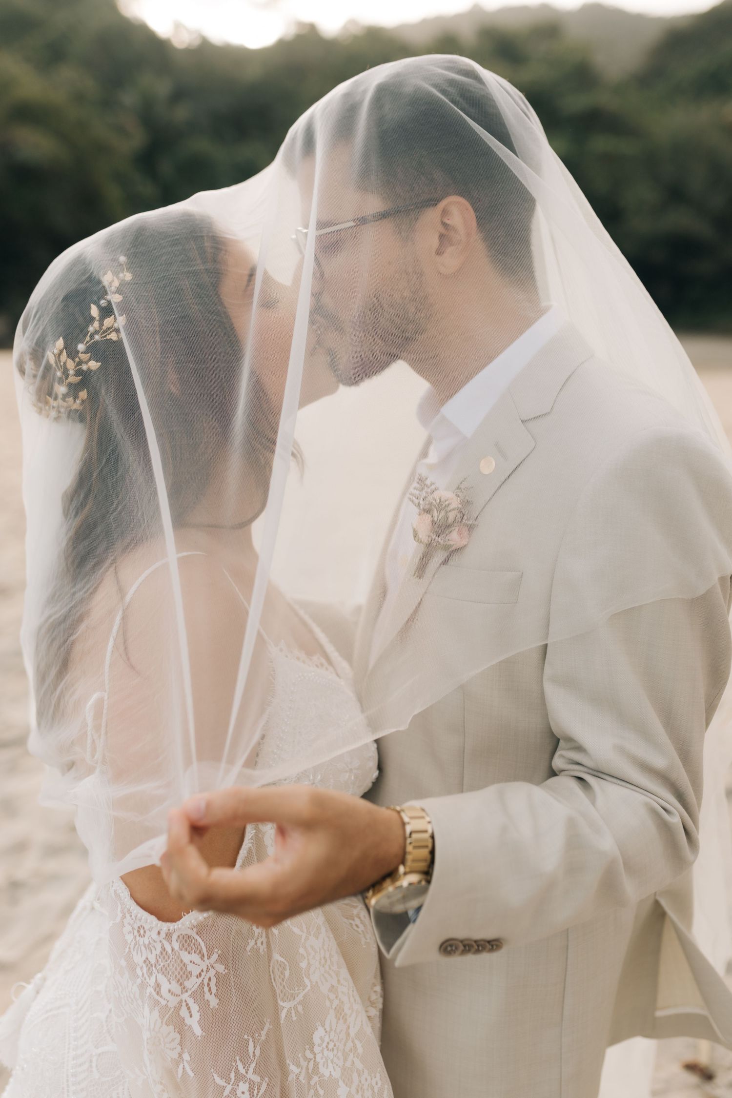 Close-up wedding portrait showing gentle intimacy between newlyweds beneath flowing white veil.