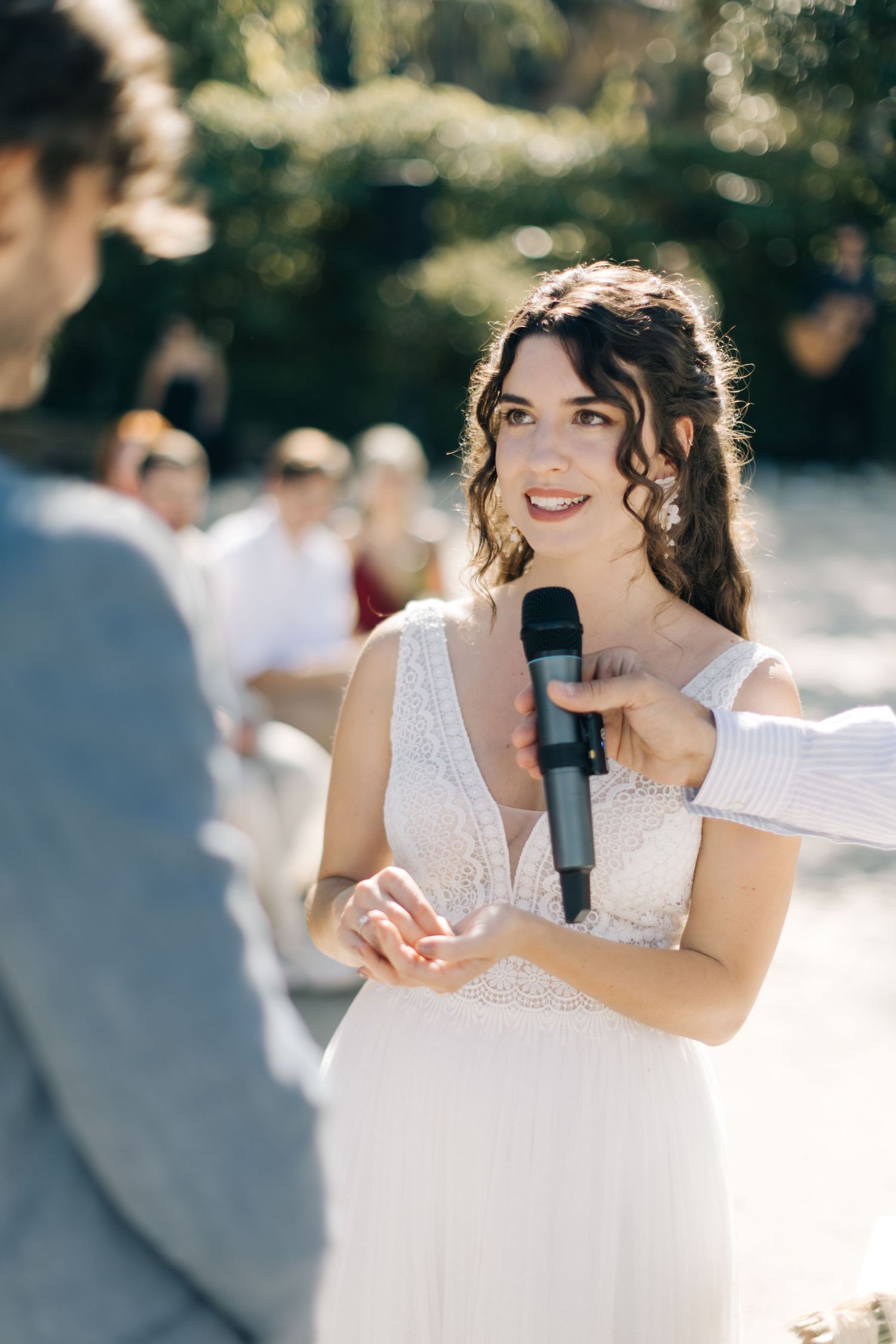Outdoor wedding ceremony with bride speaking into microphone.