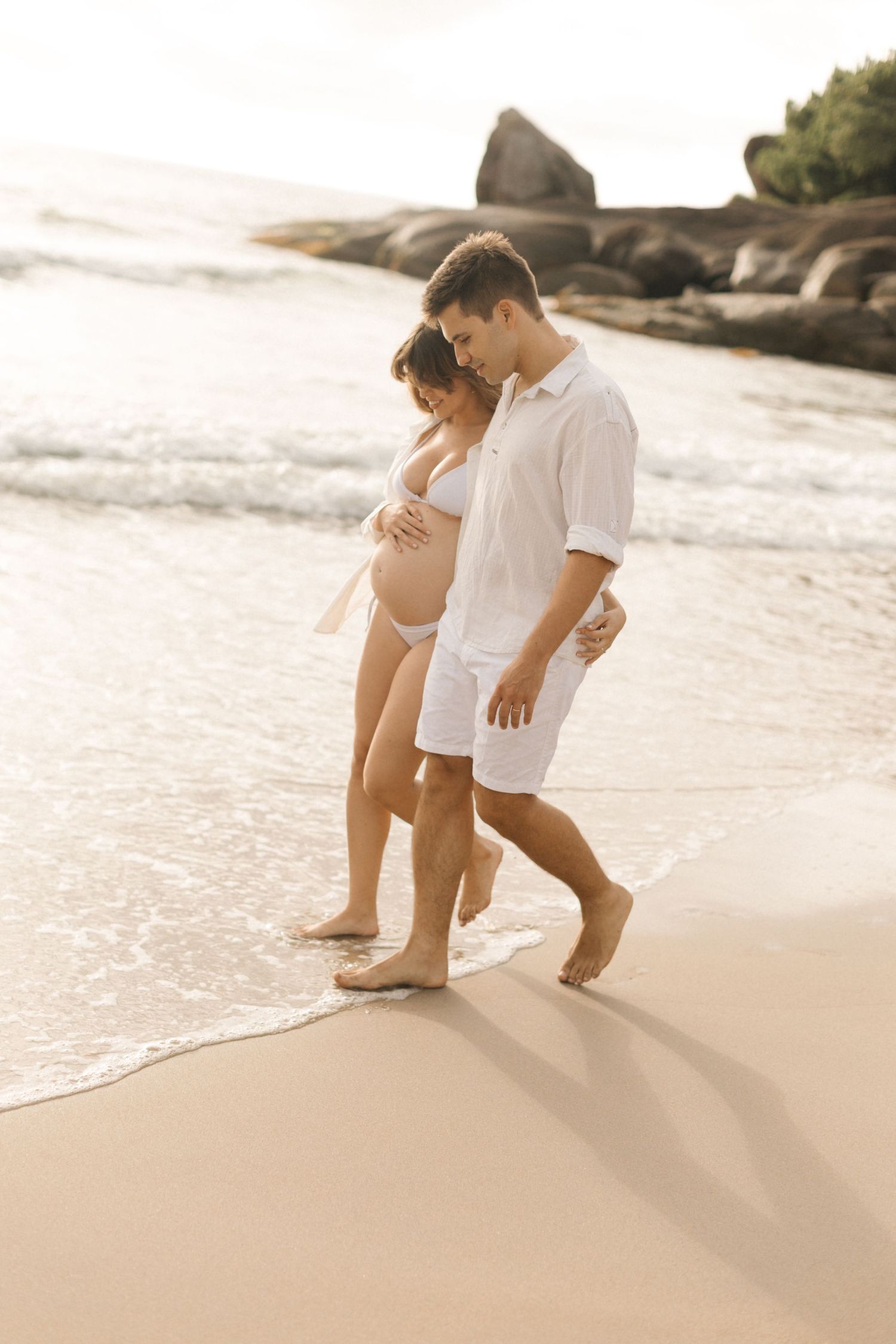 Couple playing in the shallow waves on a sandy beach.