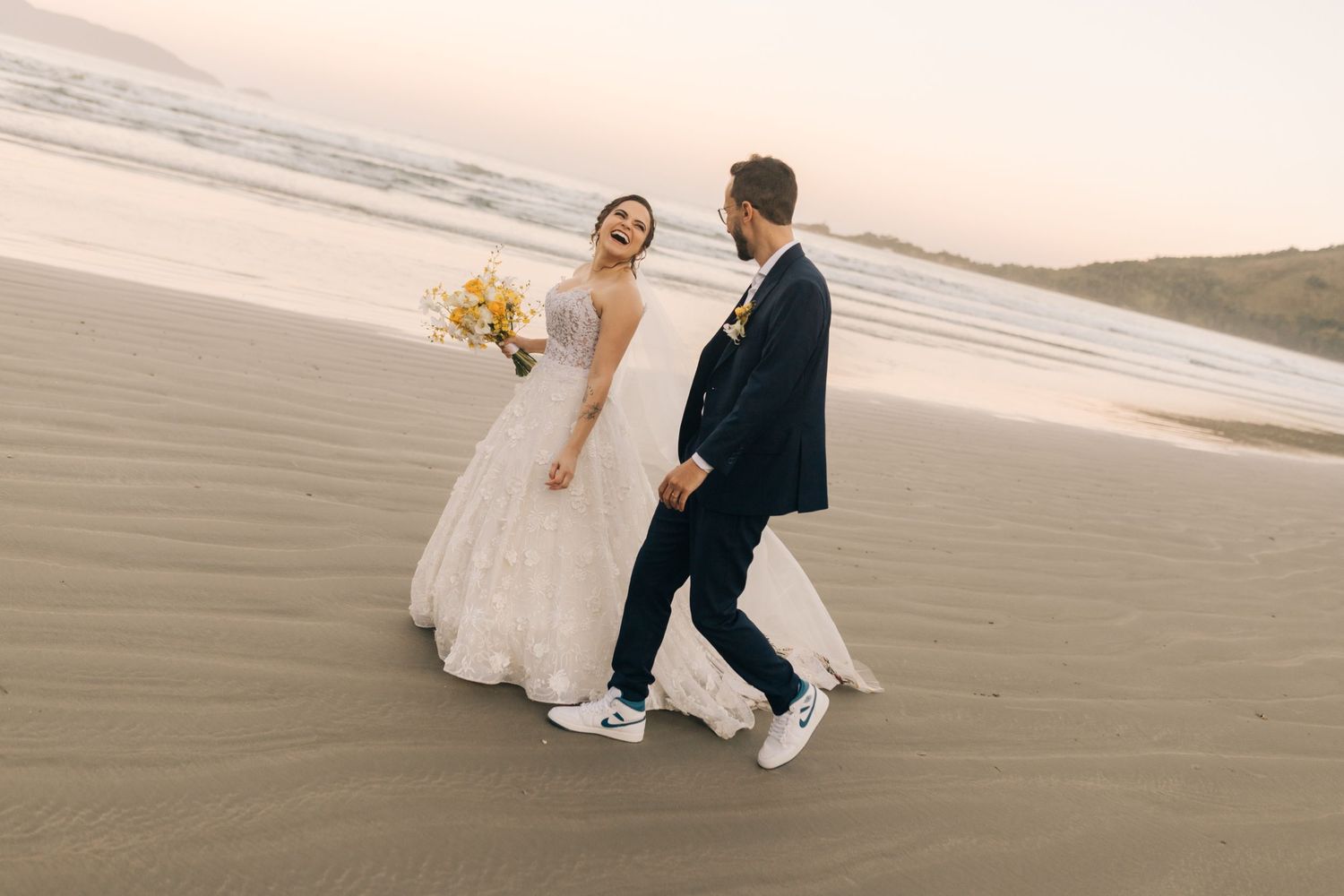 A beautiful sunset wedding photoshoot on a sandy beach with mountains in the background.