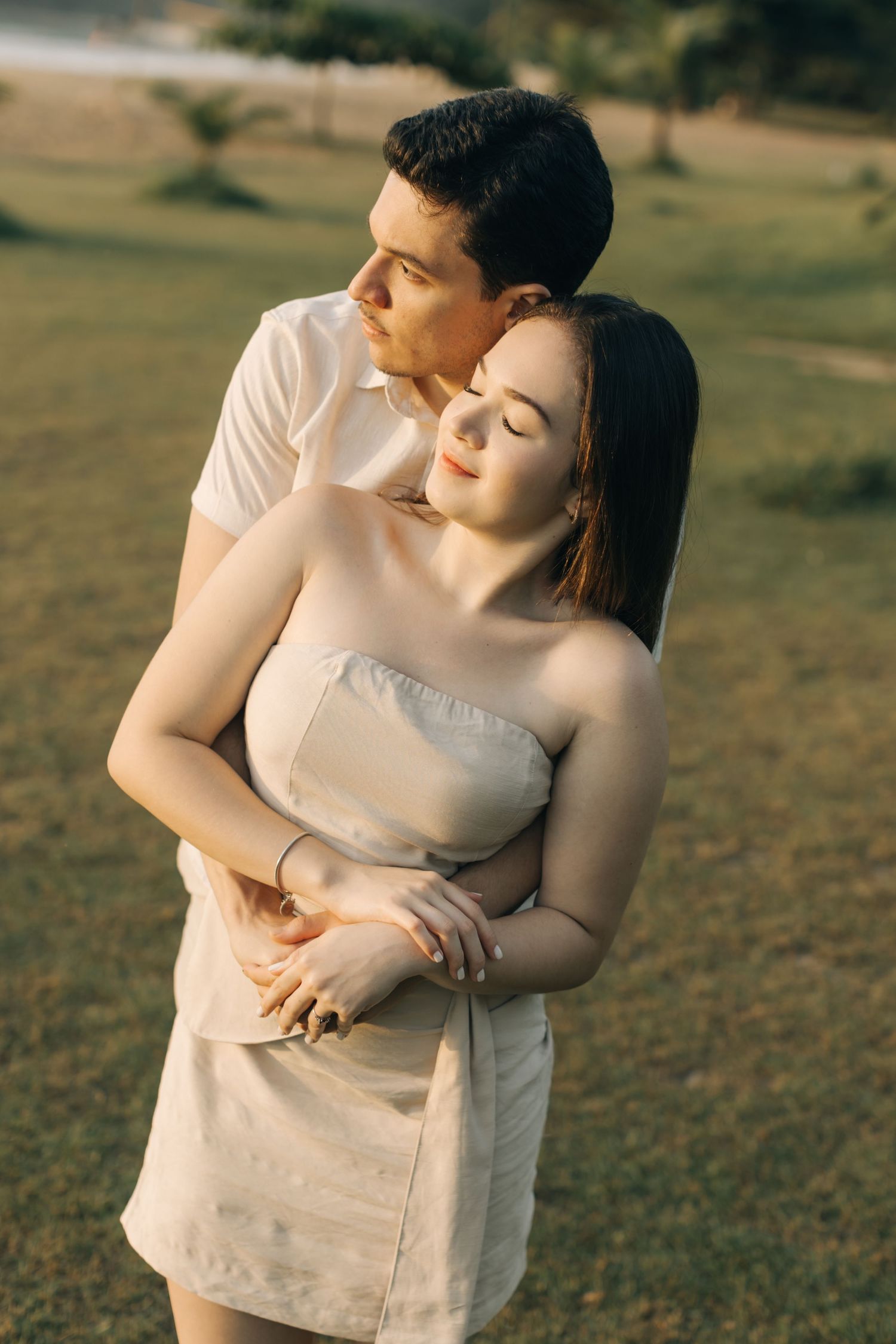 Couple in matching cream outfits sharing tender embrace during sunset portrait session.