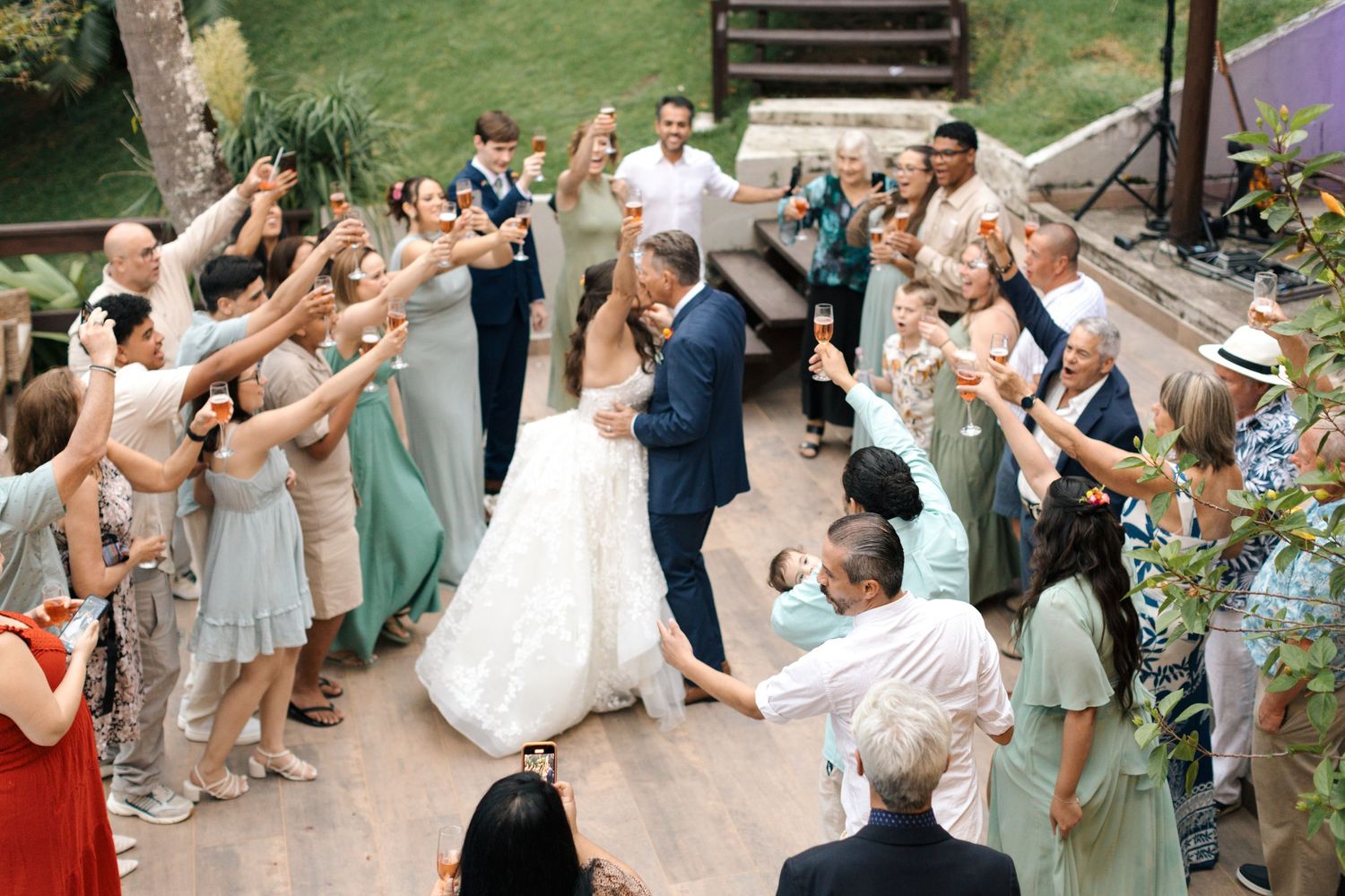 Wedding guests celebrating and cheering in an outdoor garden setting.