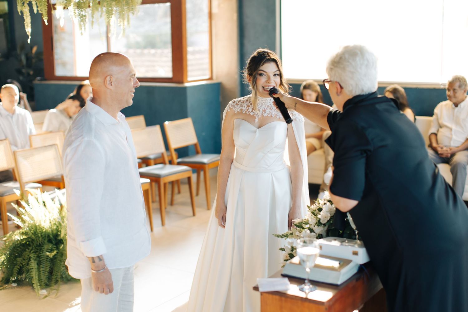 Wedding ceremony proceedings with officiant speaking at indoor venue with natural lighting.