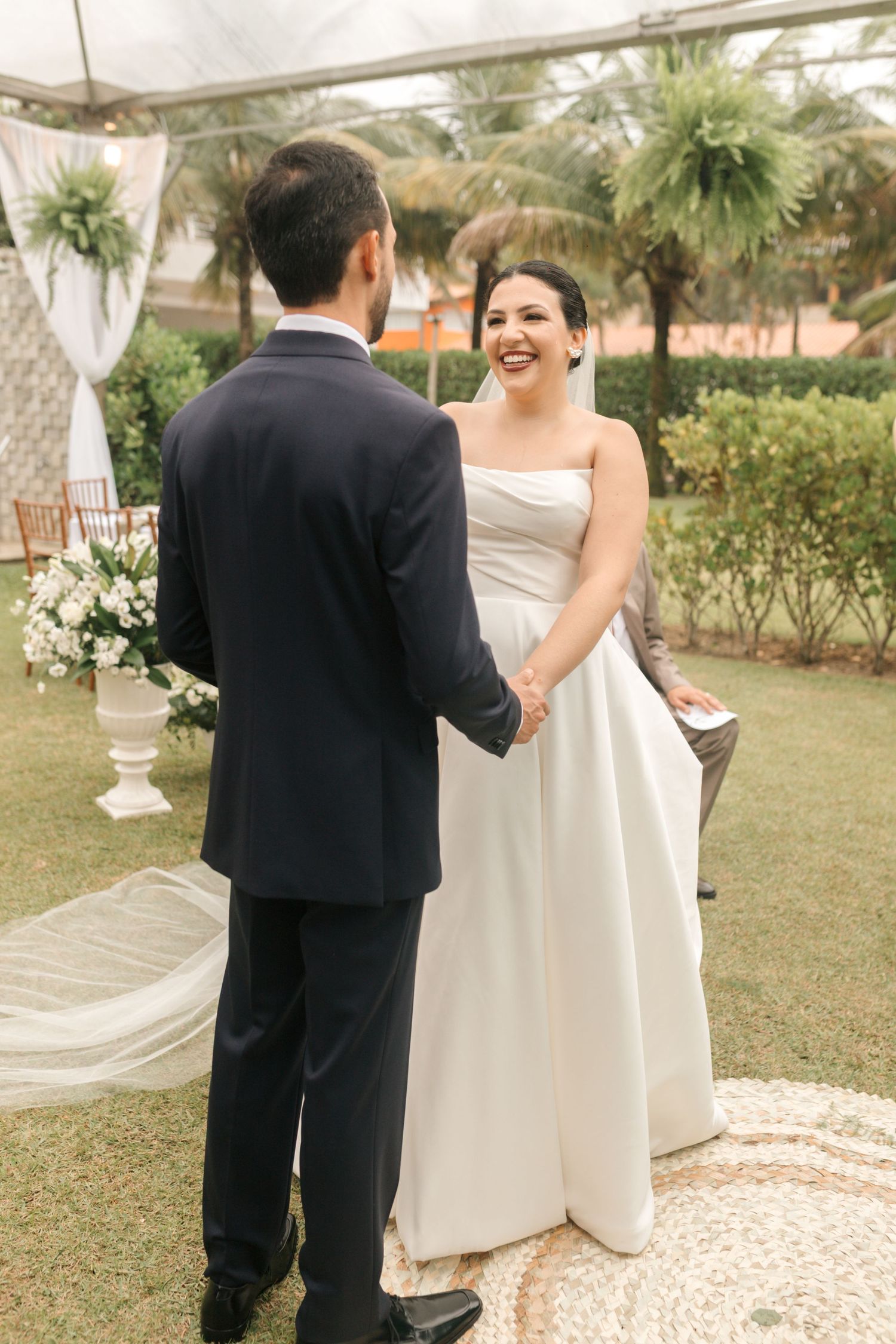 A candid moment during an outdoor wedding ceremony with a bride in white and groom in black.
