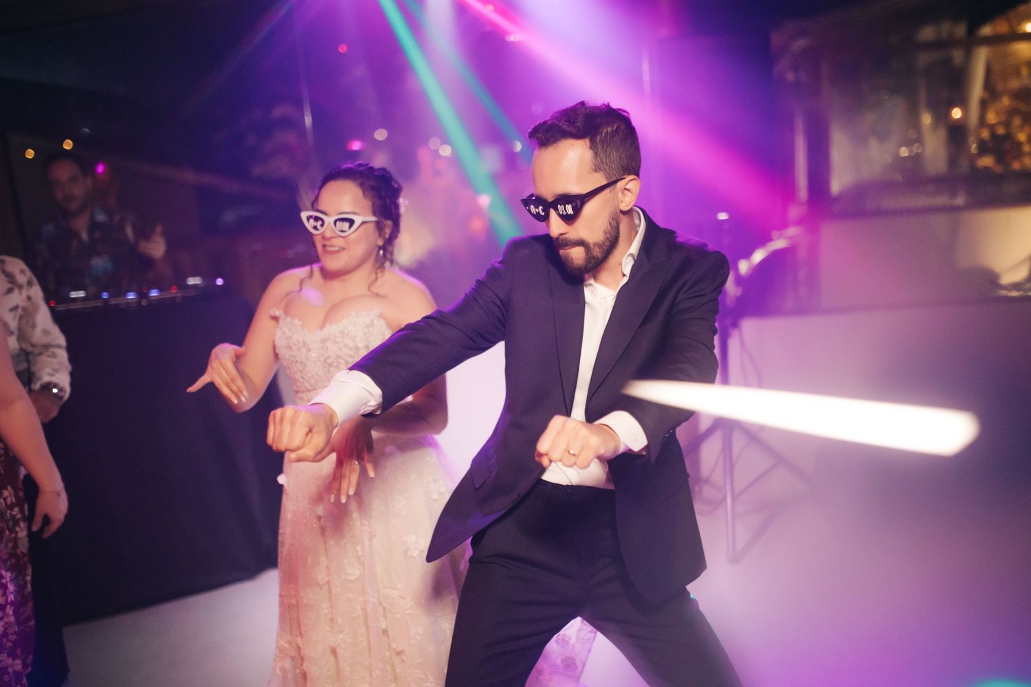 Wedding party dance floor with vibrant purple and pink lighting effects.