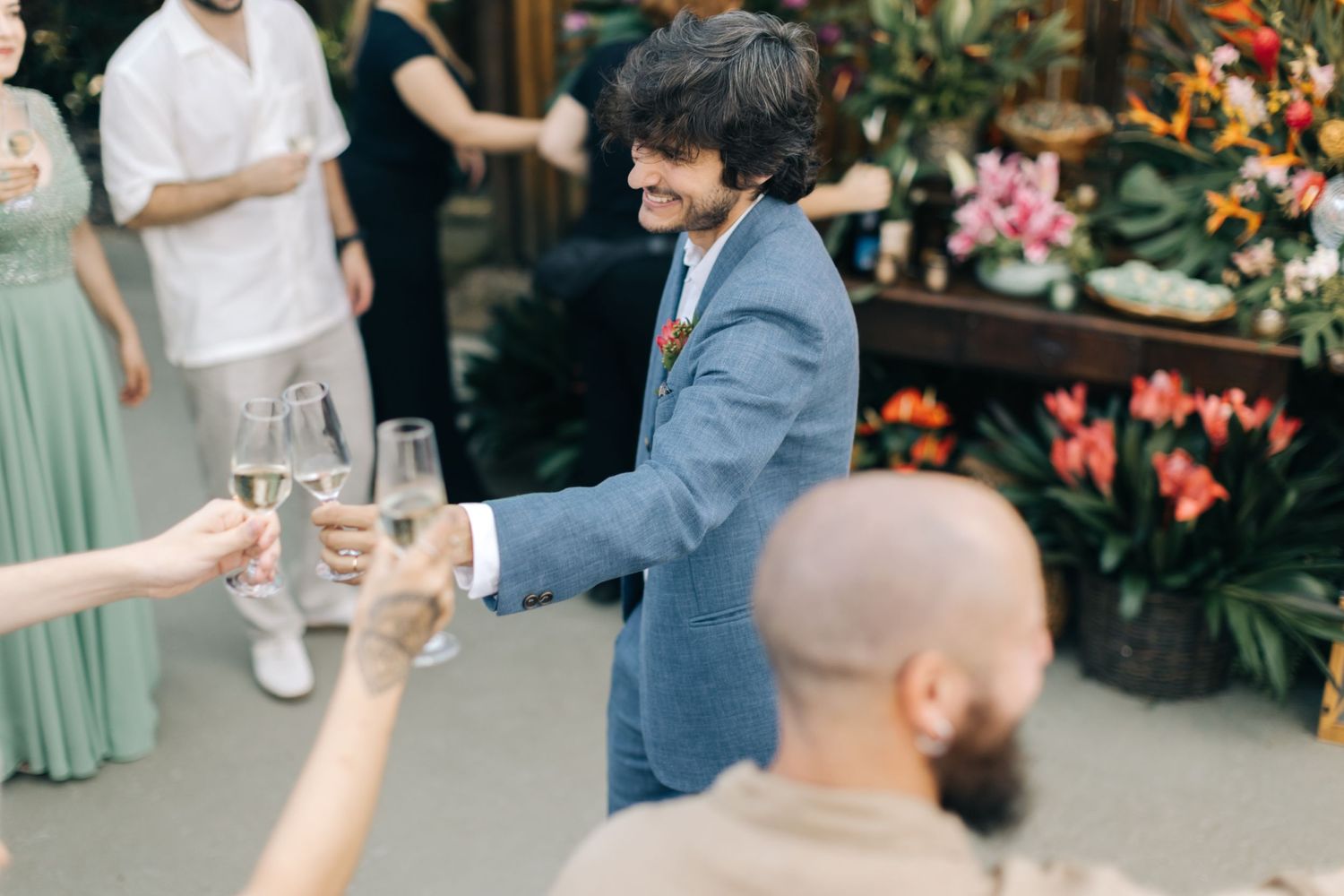 Wedding toast scene with champagne glasses and tropical decor.