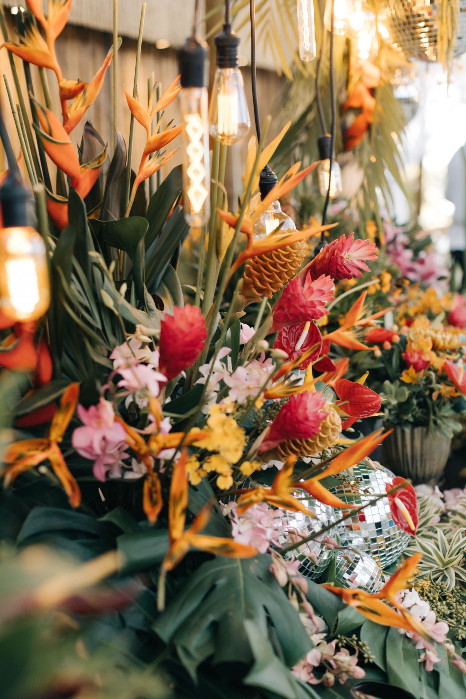 Tropical floral arrangement with orange birds of paradise, pink flowers, and lush greenery.