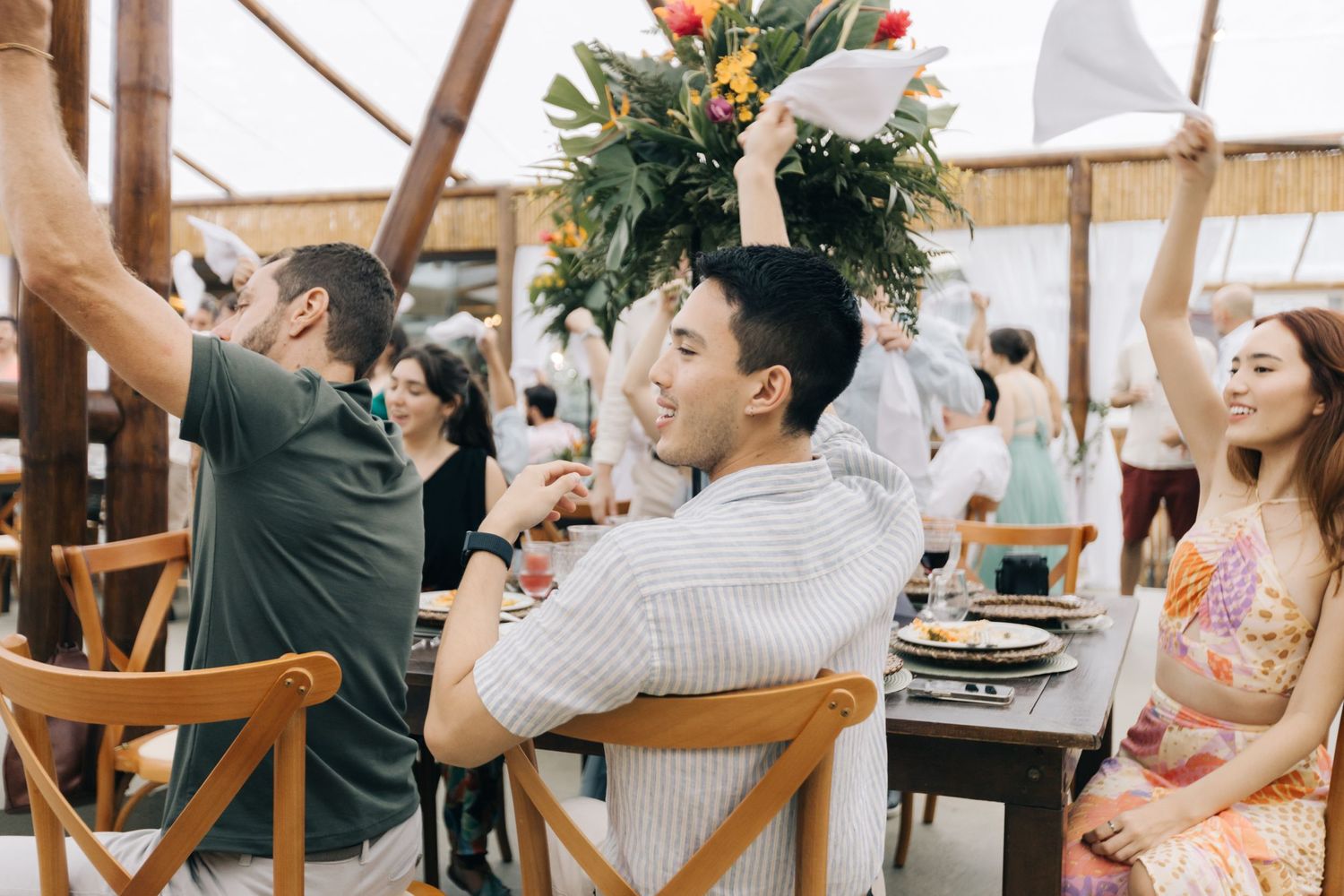 Reception guests dancing with raised arms at outdoor wedding celebration.