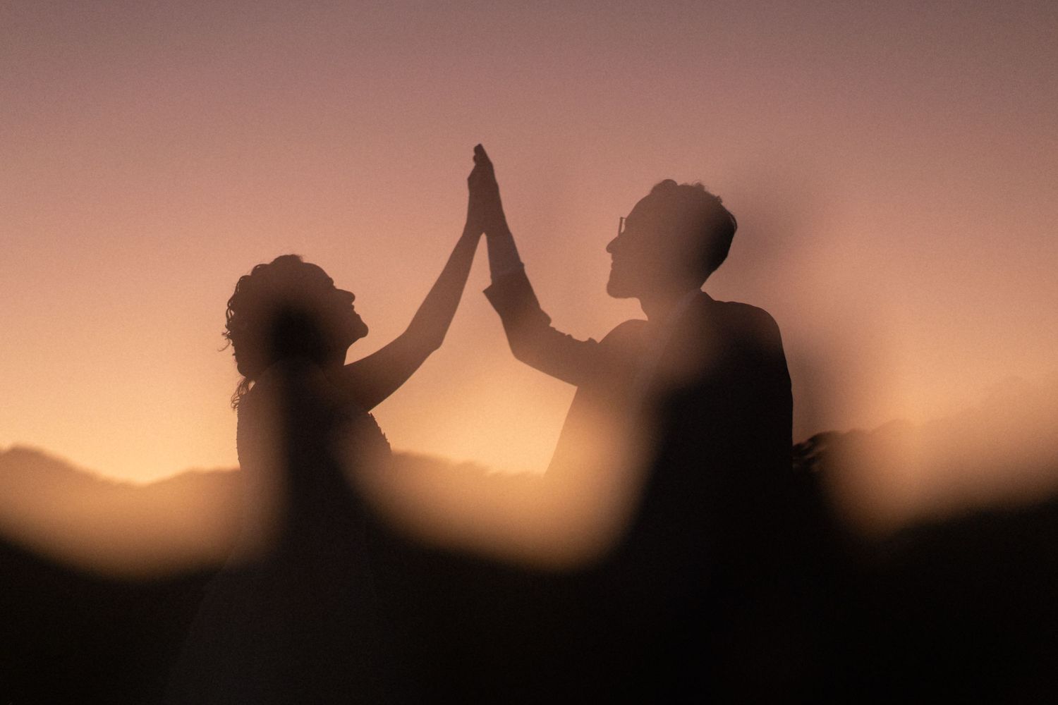 Silhouette of a couple giving high five during sunset.