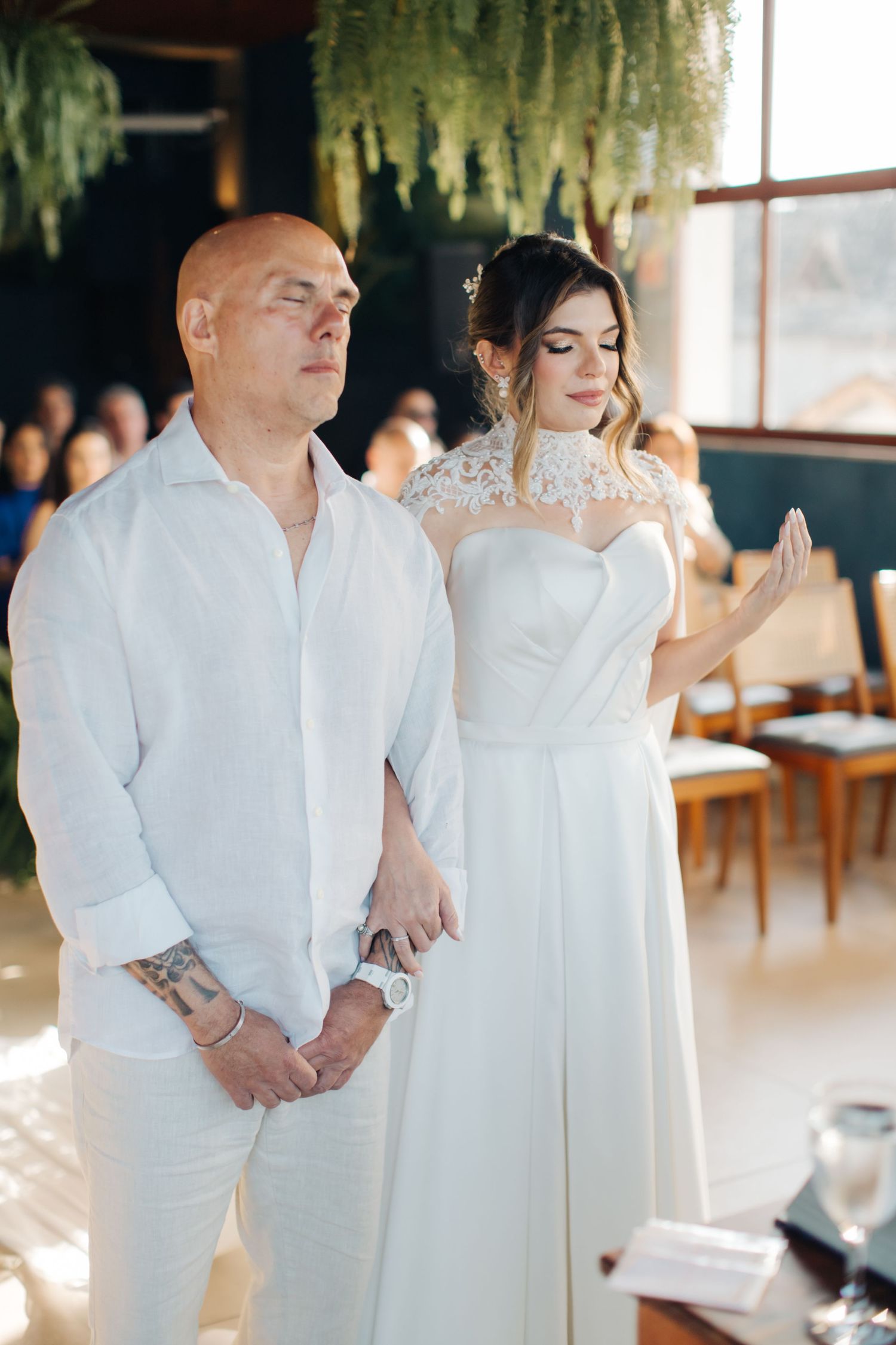 Wedding couple wearing matching white outfits walking together during ceremony.