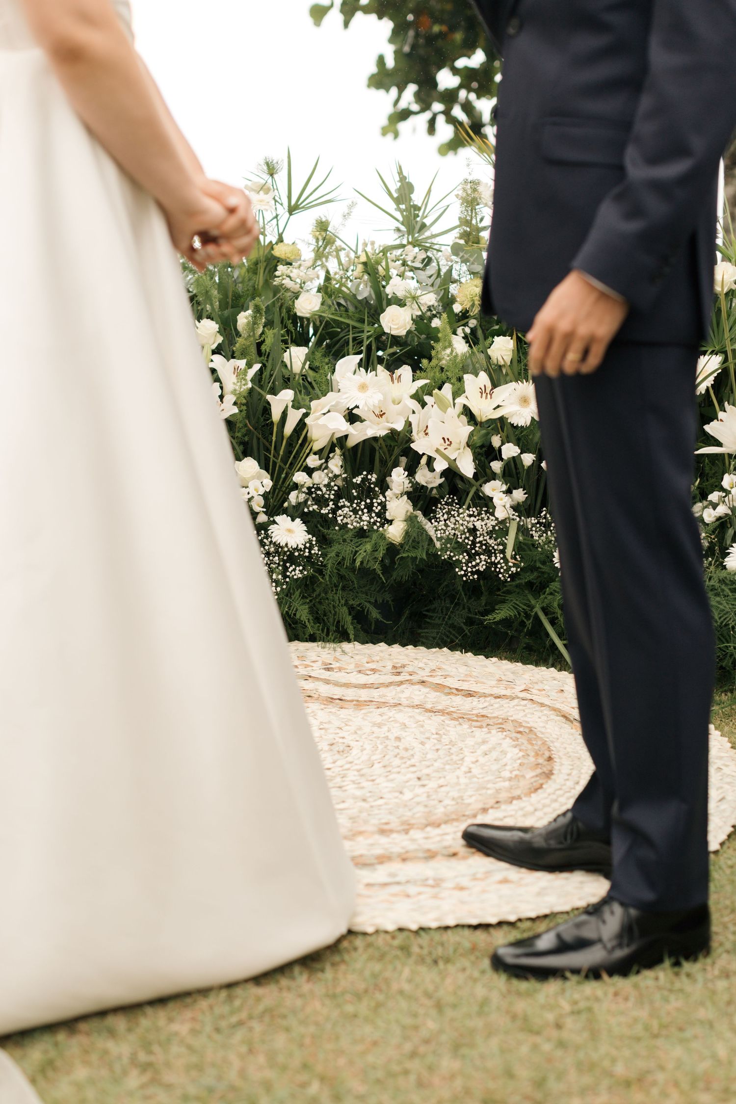 Detail shot of wedding attire and floral decorations during an outdoor ceremony.