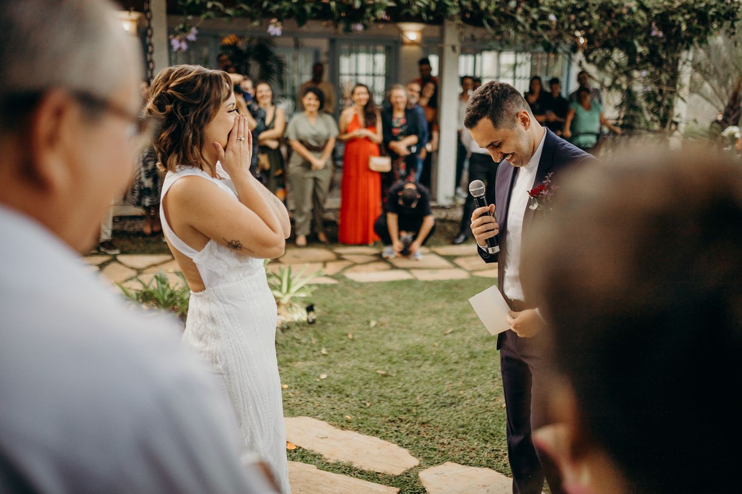 Outdoor garden wedding ceremony with guests gathered under natural lighting.