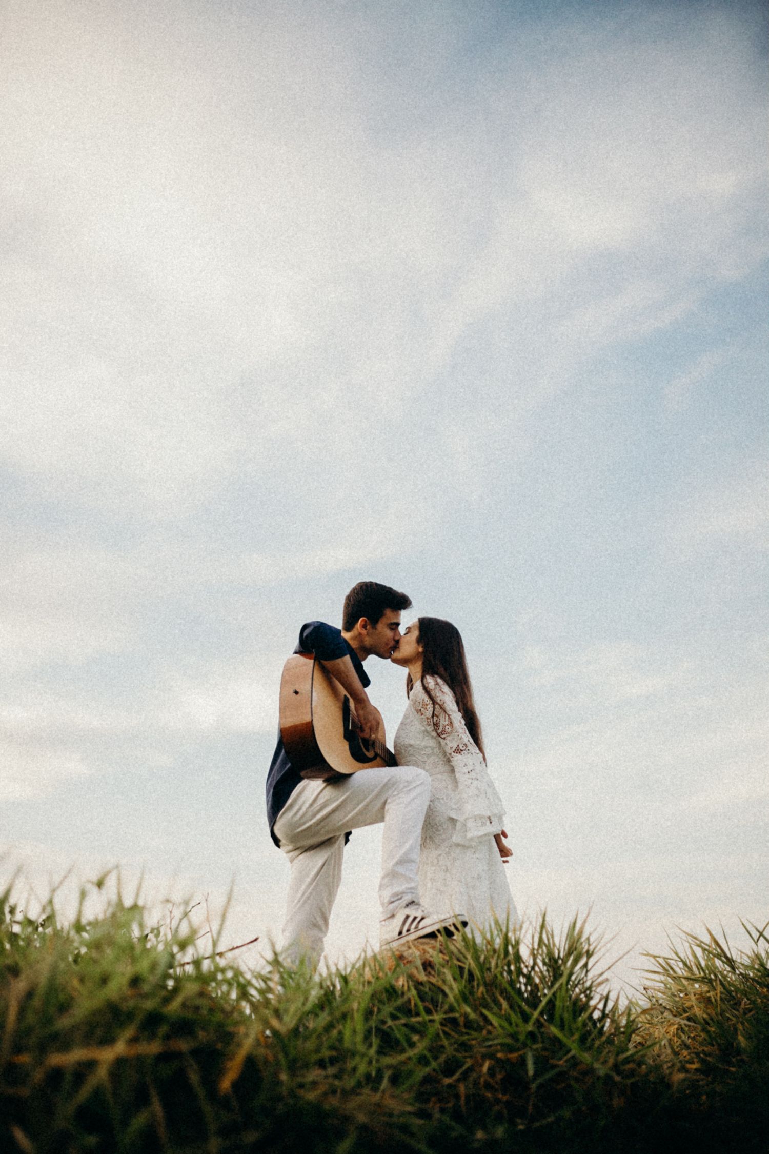 A romantic silhouette of a couple embracing on a hilltop against a cloudy sky.