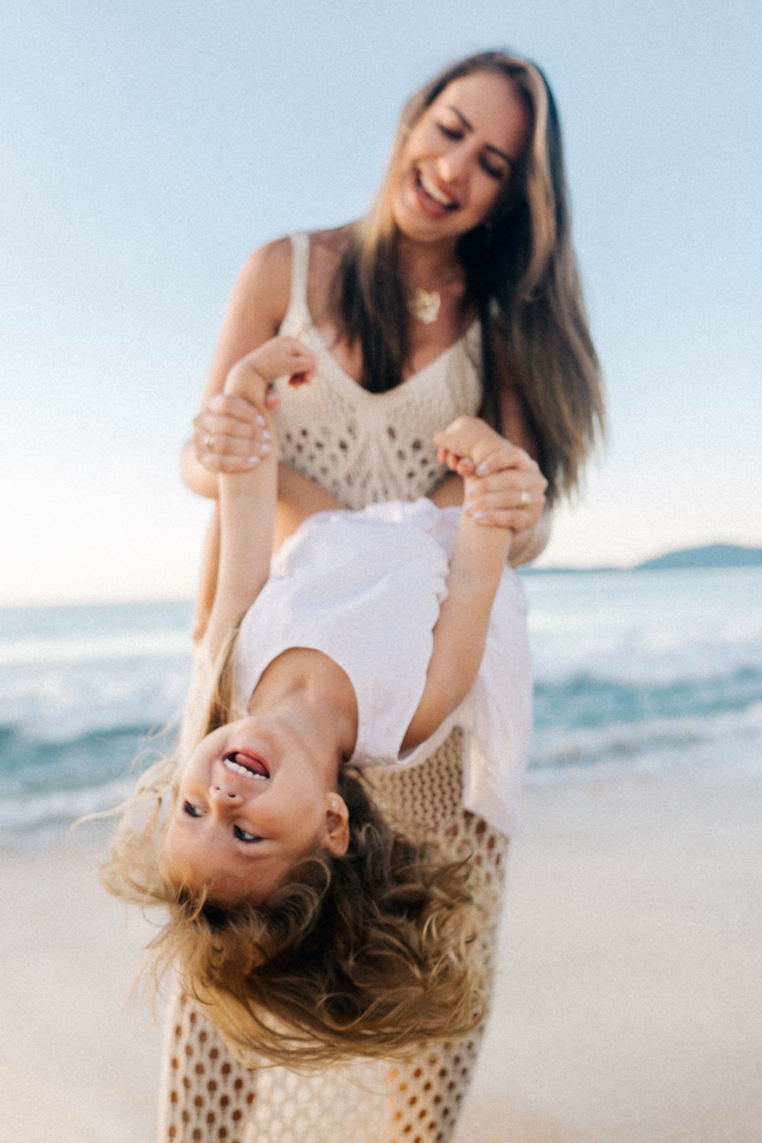 Beachside laughter during upside down play against ocean waves.