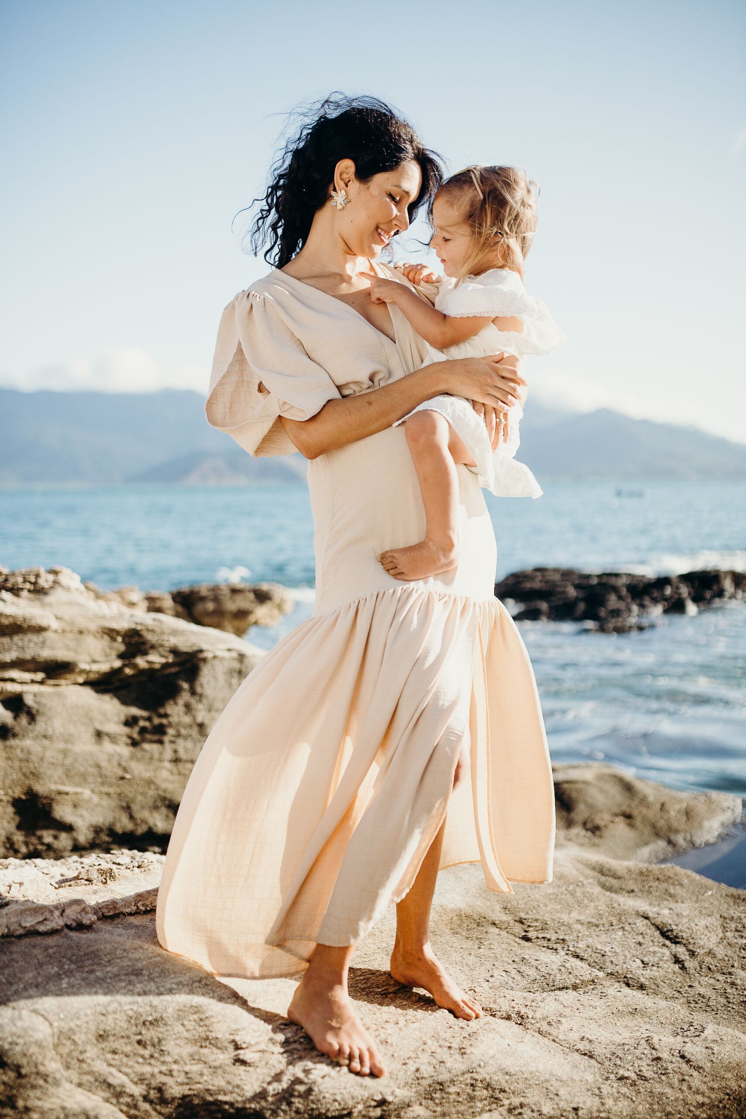 Joyful moment shared between parent and child on coastal rocks with ocean view.